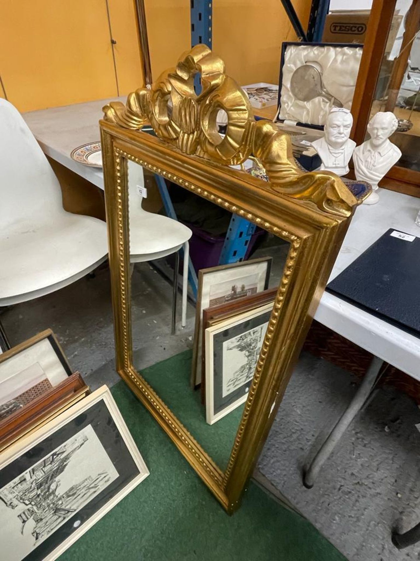 AN ORNATE GILT FRAMED MIRROR WITH RIBBON DESIGN TOP