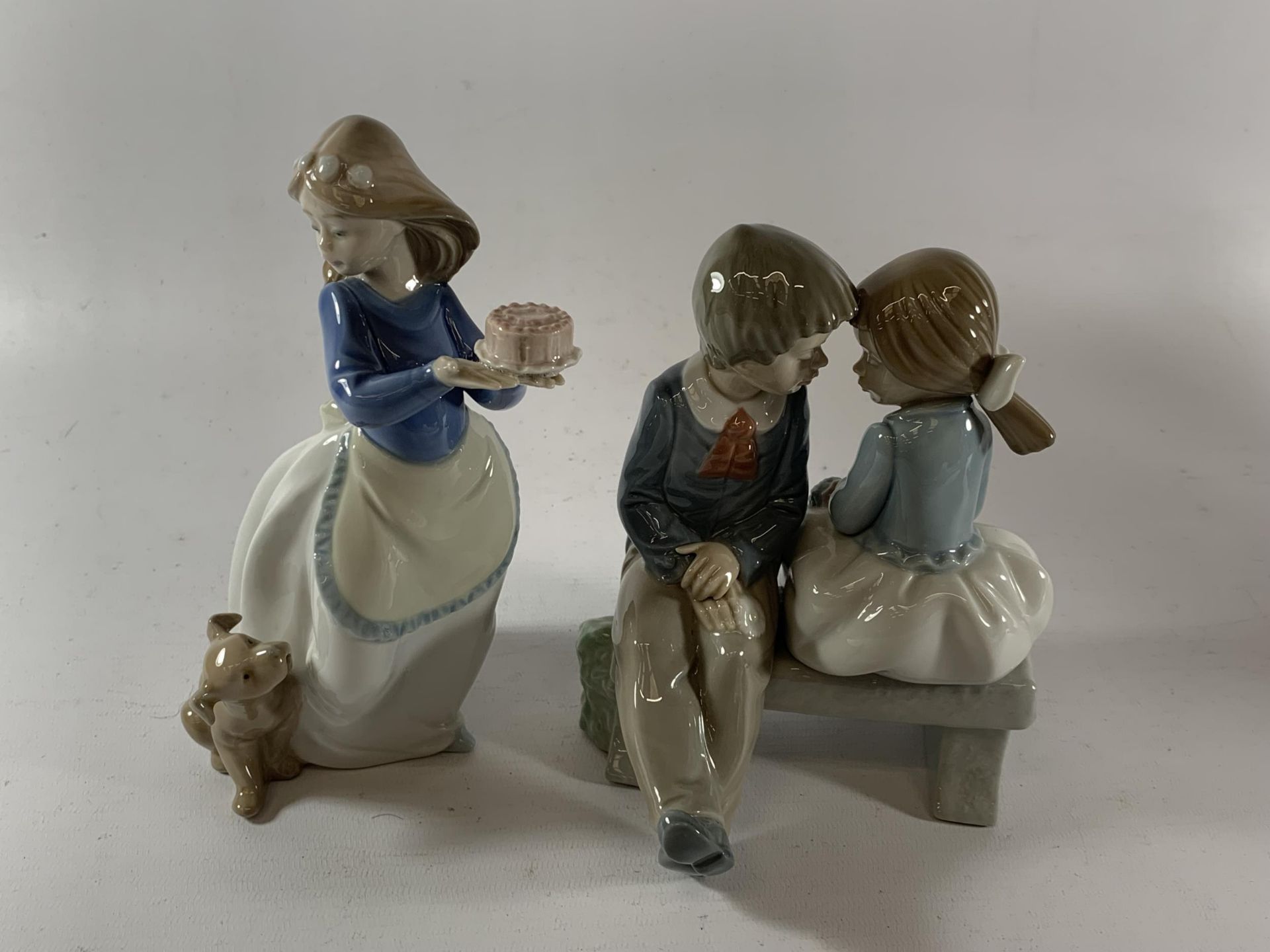 TWO NAO FIGURES - GIRL WITH CAKE AND CHILDREN ON A BENCH