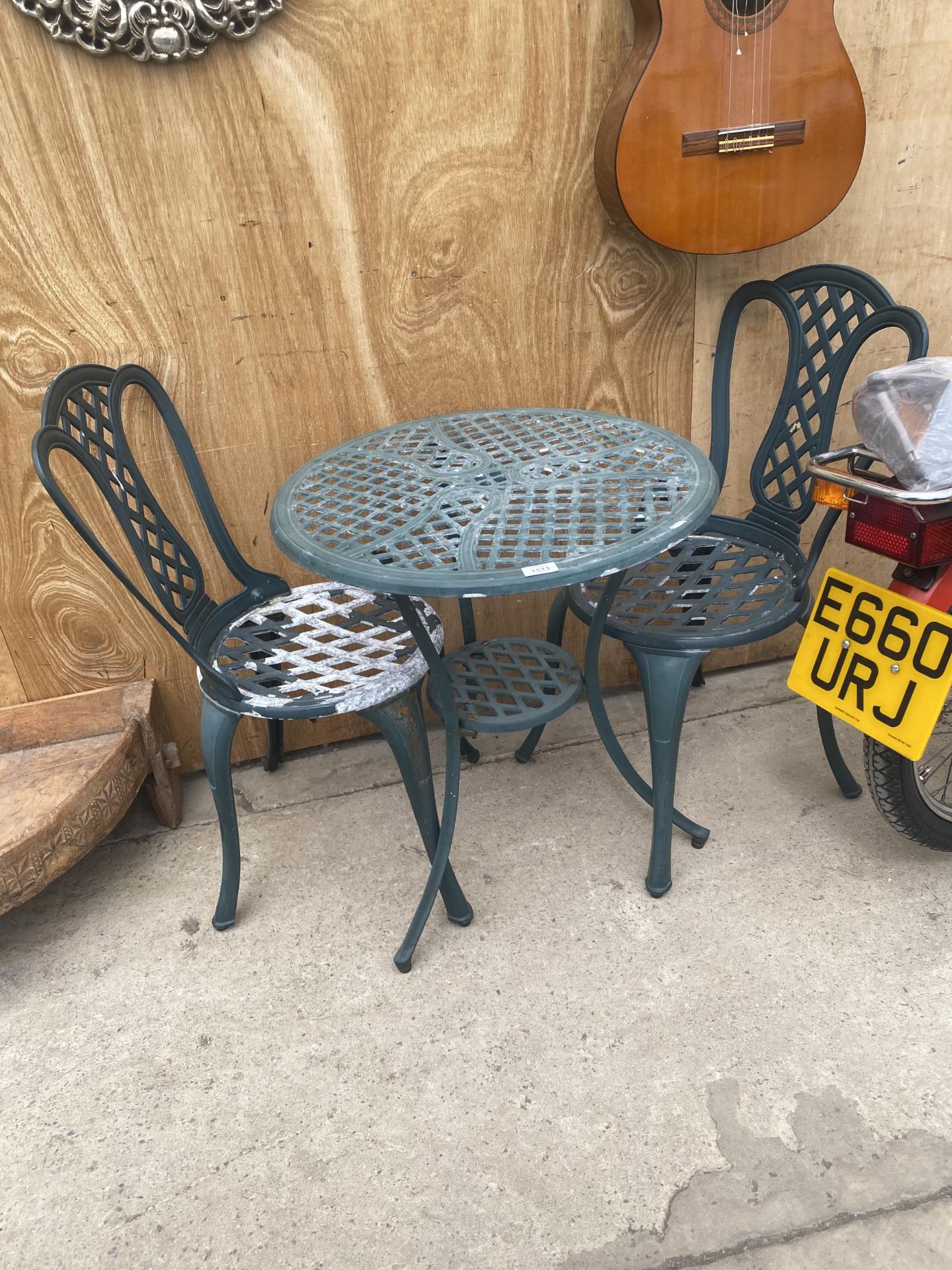 A CAST ALLOY BISTRO SET COMPRISING OF A ROUND TABLE AND TWO CHAIRS