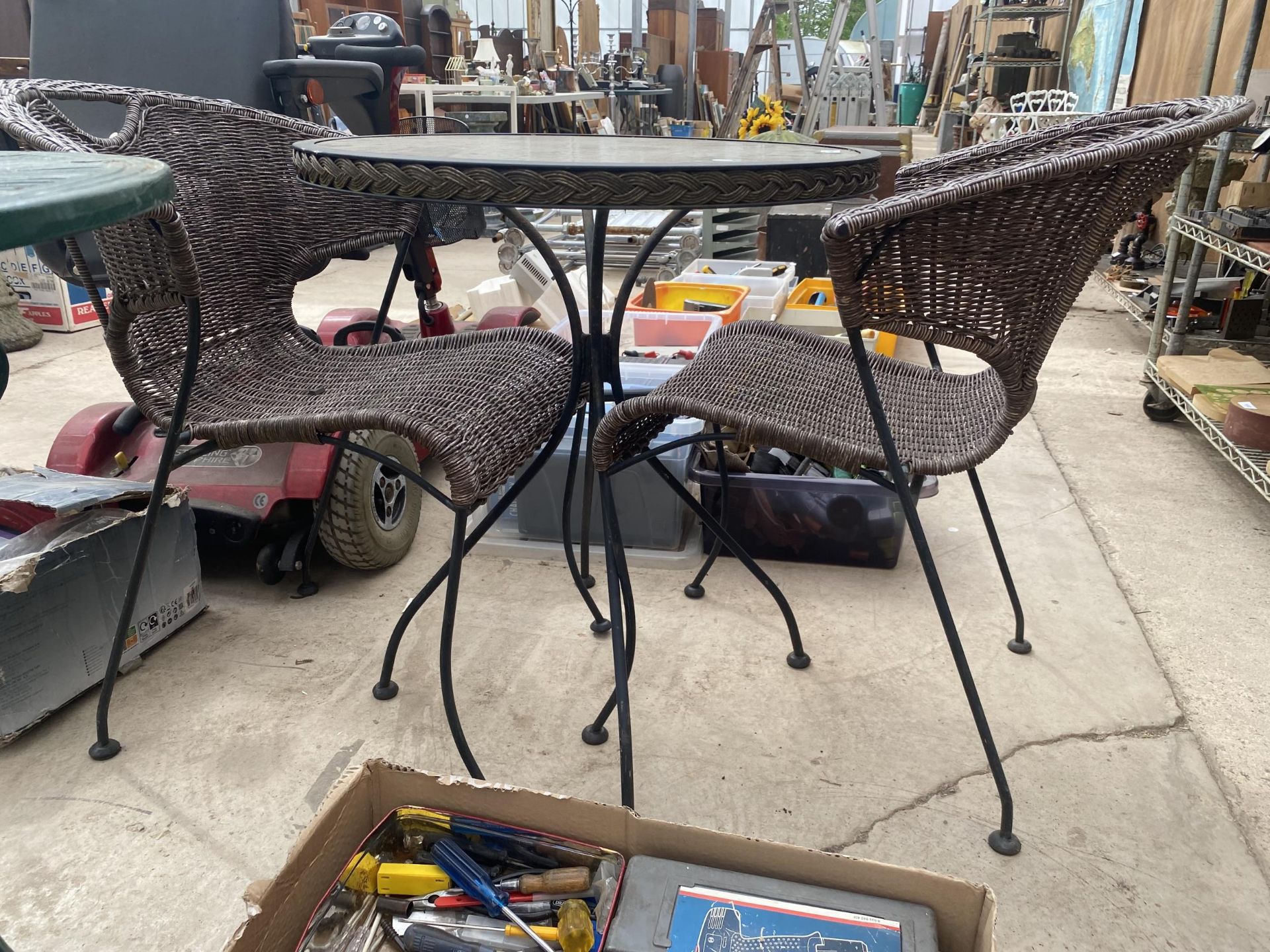 A ROUND GLASS TOPPED BISTRO TABLE AND TWO RATTAN STYLE CHAIRS - Image 2 of 2