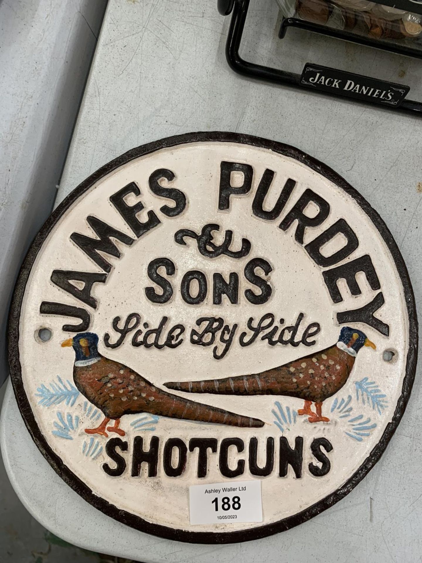 A CAST 'JAMES PURDEY & SONS SHOTGUNS' SIGN DIAMETER 23CM