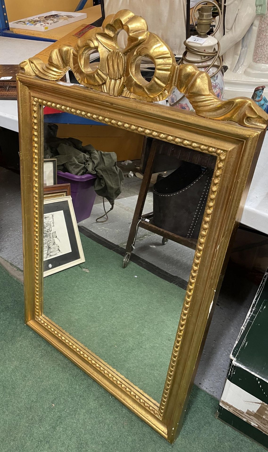 AN ORNATE GILT FRAMED MIRROR WITH RIBBON DESIGN TOP