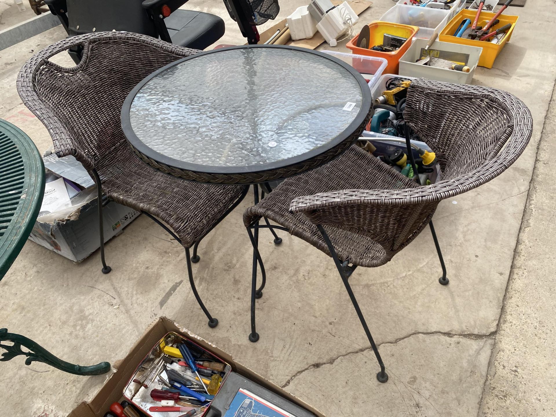 A ROUND GLASS TOPPED BISTRO TABLE AND TWO RATTAN STYLE CHAIRS