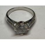 A SILVER RING WITH A LARGE SOLITAIRE CLEAR STONE AND CLEARSTONES TOO SHOULDERS SIZE M/N IN A
