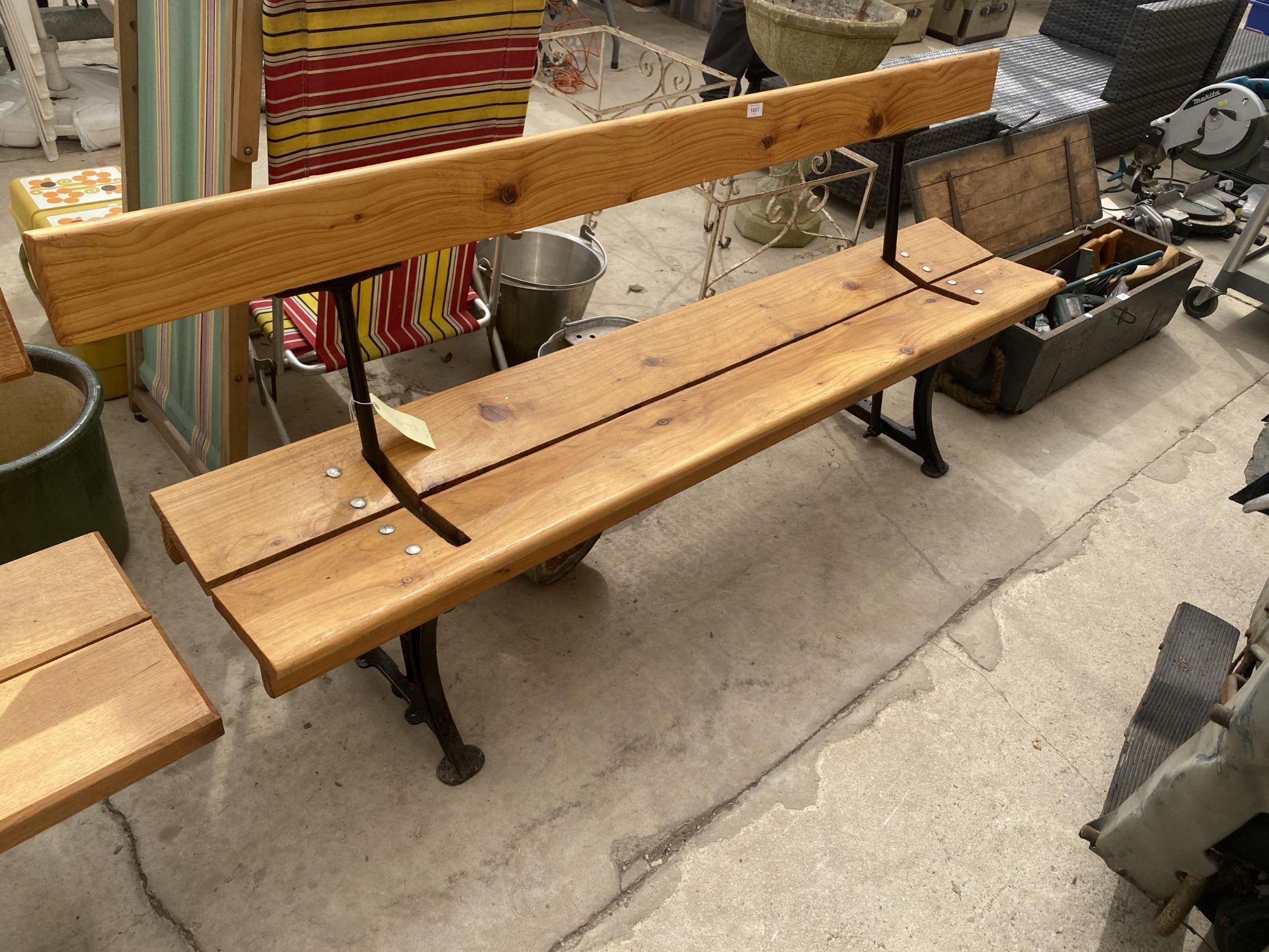 A LARGE WOODEN REVERSABLE RAILWAY BENCH WITH CAST LEGS