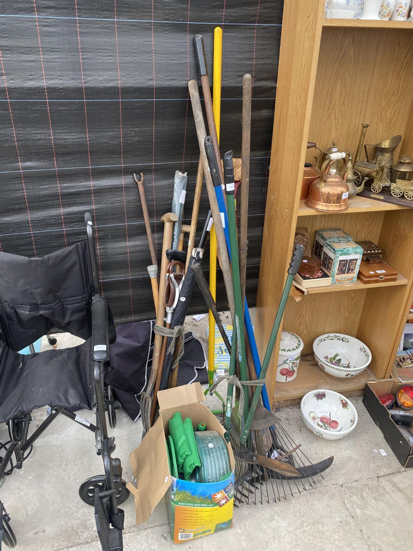 AN ASSORTMENT OF GARDEN TOOLS TO INCLUDE RAKES, FORKS AND A HOSE REEL ETC