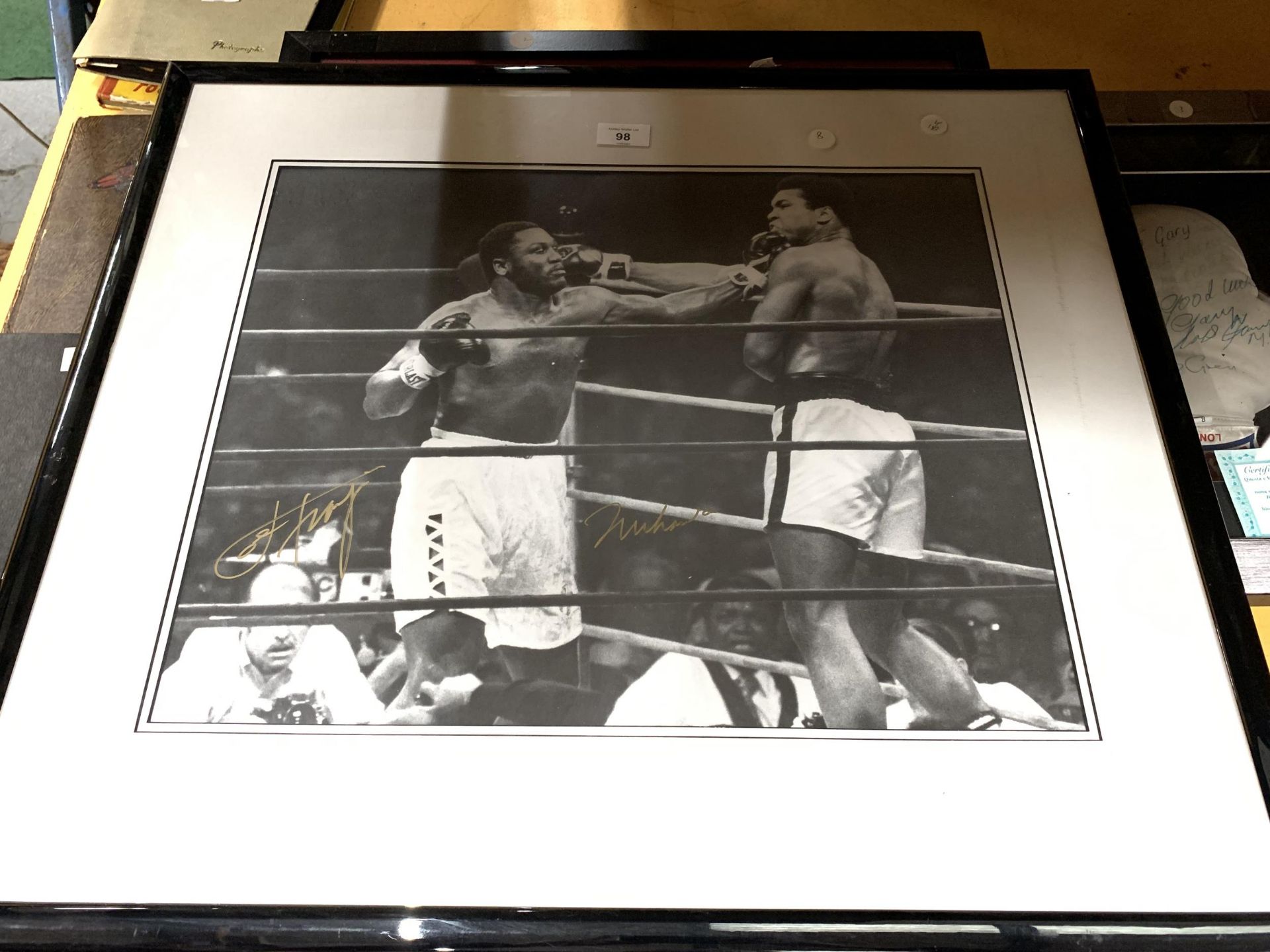 A SIGNED AND FRAMED BLACK AND WHITE PHOTOGRAPH OF MUHAMMED ALI AND JOE FRAZIER WITH CERTIFICATE