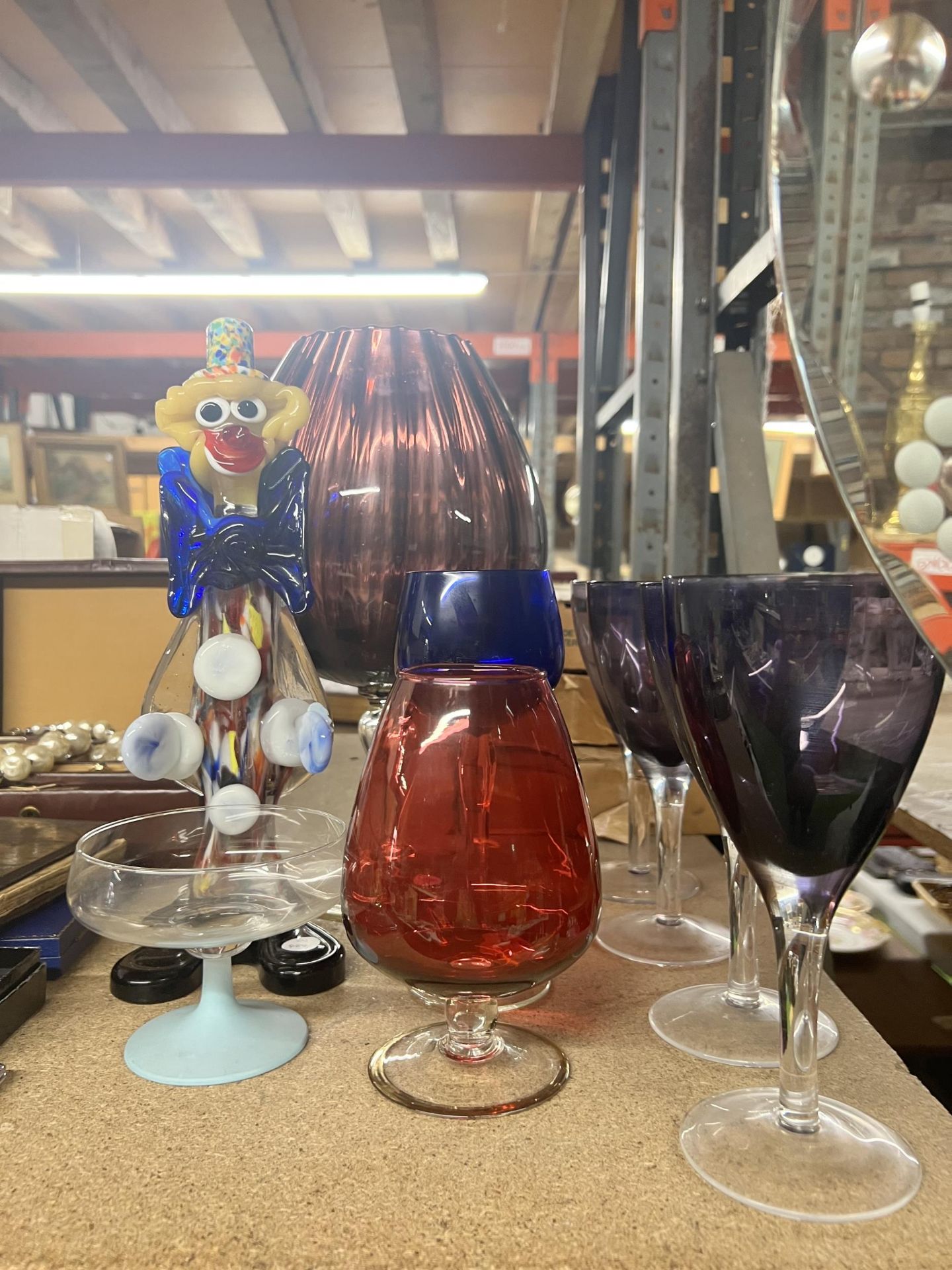 A QUANTITY OF COLOURED GLASSWARE TO INCLUDE A MURANO STYLE CLOWN, LARGE BRANDY BALLOON, WINE