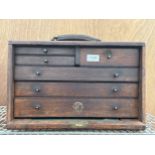 A VINTAGE MINIATURE OAK ENGINEERS CHEST WITH THREE LONG AND THREE SHORT DRAWERS AND A DROP DOWN