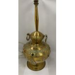 A VINTAGE MIDDLE EASTERN DESIGN BRASS LAMP WITH EMBOSSED STONE AND BUDDHA DESIGN, HEIGHT 58CM