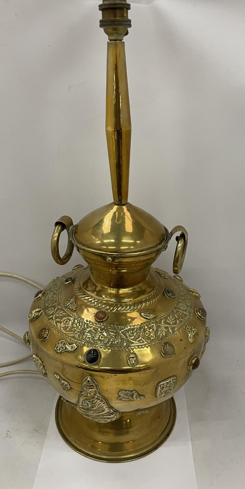 A VINTAGE MIDDLE EASTERN DESIGN BRASS LAMP WITH EMBOSSED STONE AND BUDDHA DESIGN, HEIGHT 58CM