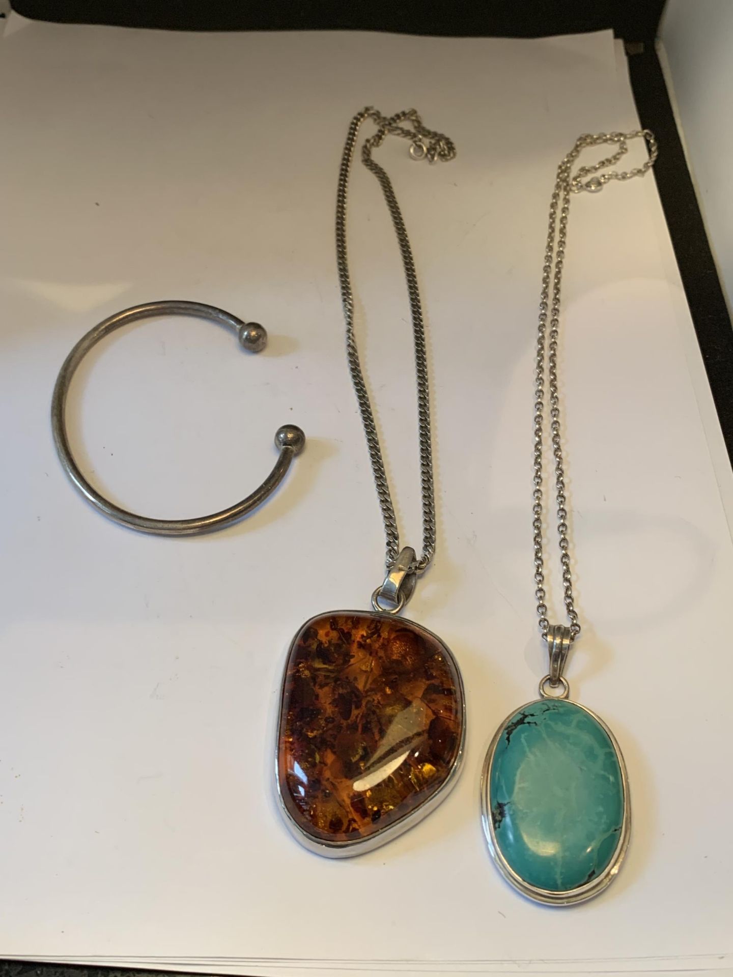 TWO SILVER NECKLACES WITH LARGE PENDANTS AND A SILVER BANGLE