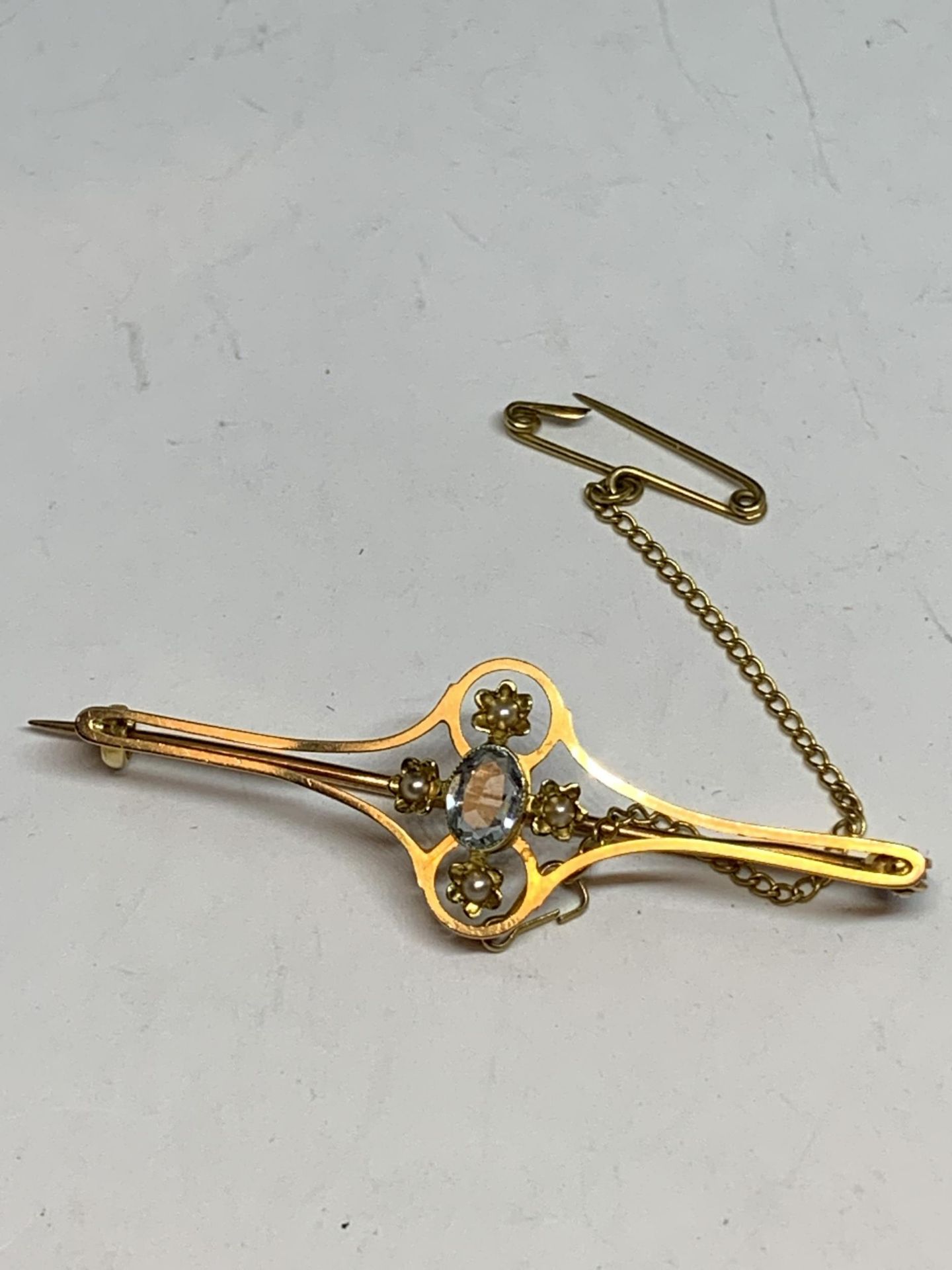 A TESTED TO 18 CARAT GOLD BROOCH WITH A CENTRE AQUAMARINE, PEARLS AND A SAFETY CHAIN GROSS WEIGHT