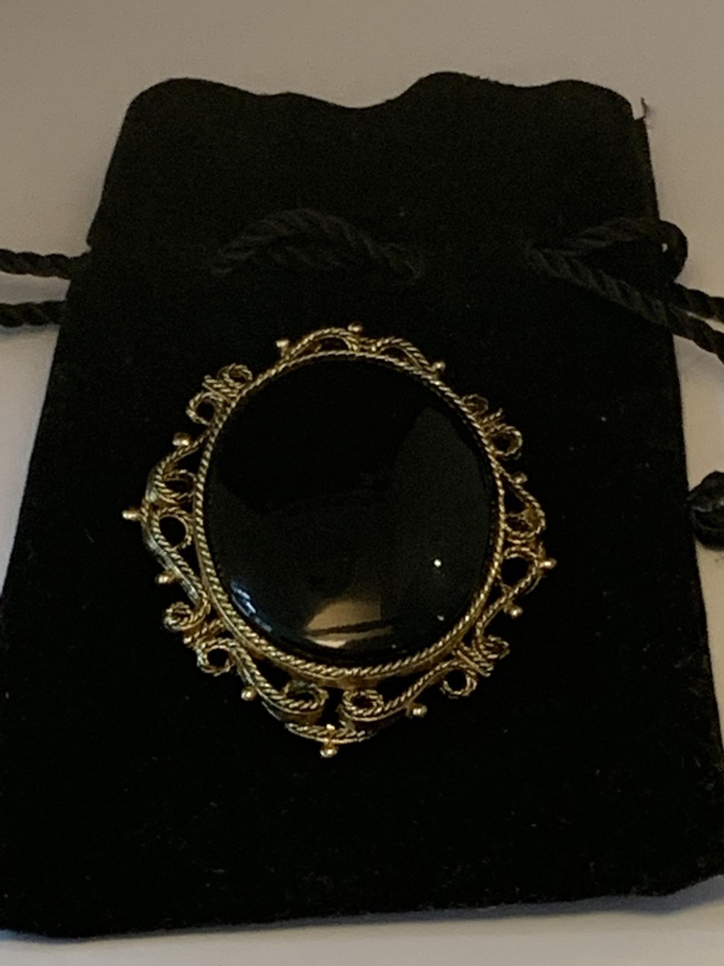 A LARGE BROOCH WITH BLACK STONE WITH ORNATE YELLOW METAL SURROUND MARKED 250 WITH PRESENTATION BAG - Image 4 of 4