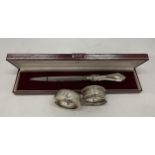 A CASED HALLMARKED SILVER HANDLED LETTER OPENER AND TWO HALLMARKED SILVER NAPKIN RINGS, TOTAL WEIGHT