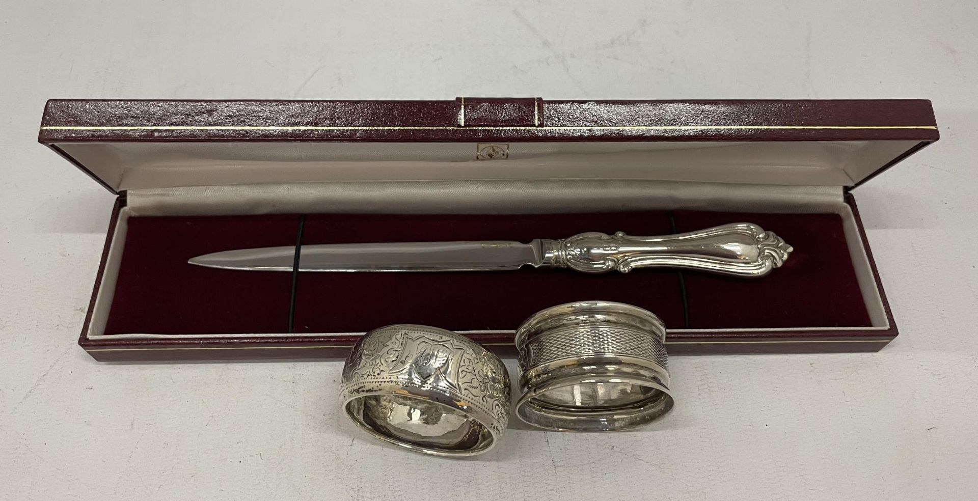 A CASED HALLMARKED SILVER HANDLED LETTER OPENER AND TWO HALLMARKED SILVER NAPKIN RINGS, TOTAL WEIGHT