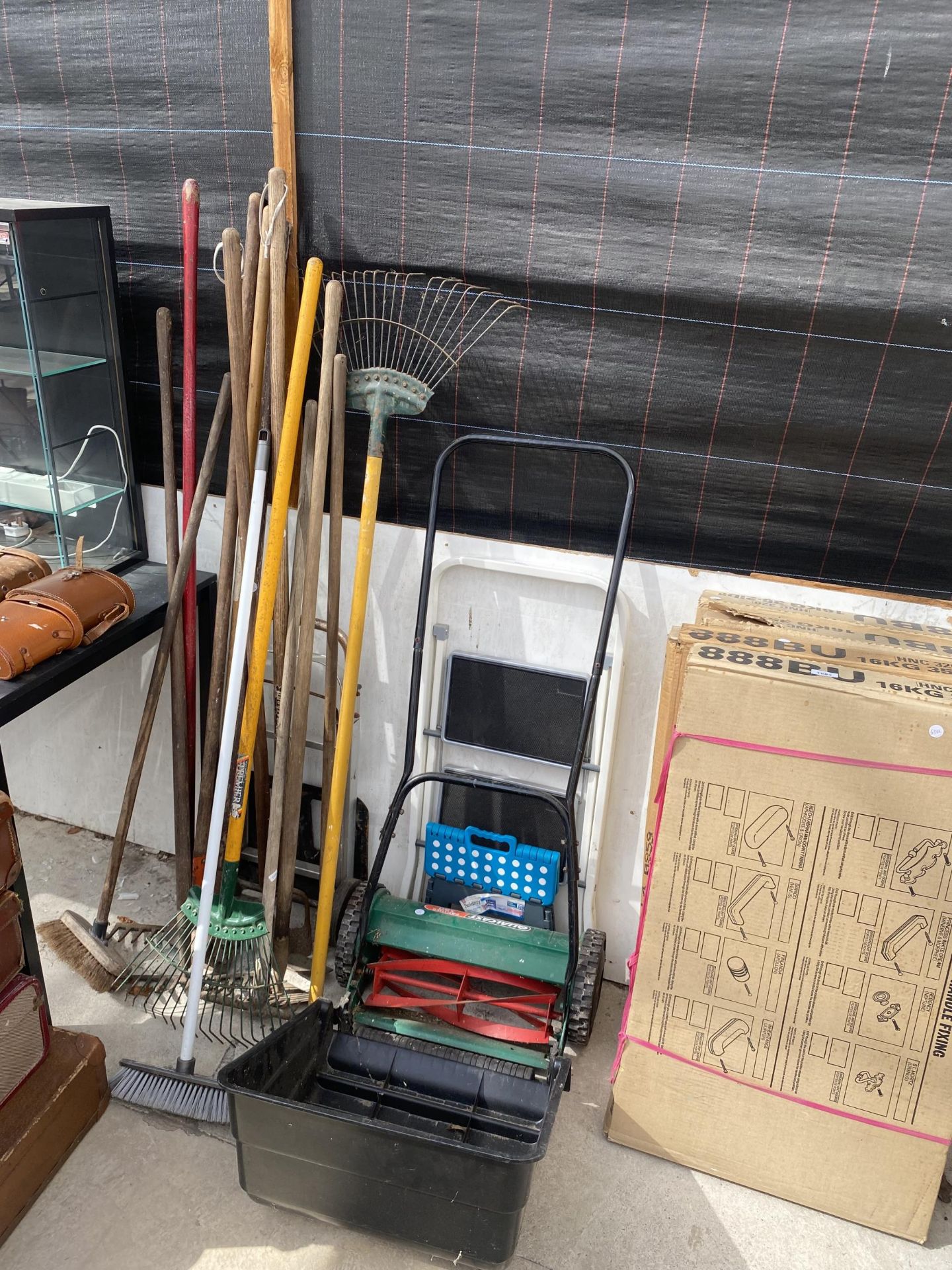 AN ASSORTMENT OF GARDEN TOOLS TO INCLUDE RAKES, A QUALCAST PANTHER AND HOES ETC