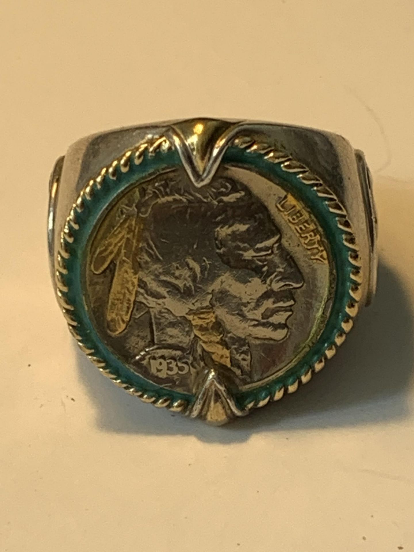 A LARGE RING WITH A FIVE CENT COIN ENGRAVED 'INDIAN HEAD NICKEL HONOURING THE AMERICAN WEST'