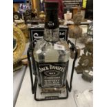 A JACK DANIELS SWINGING BOTTLE STAND WITH LARGE JACK DANIELS BOTTLE CONTAINING COINS PLUS TWO