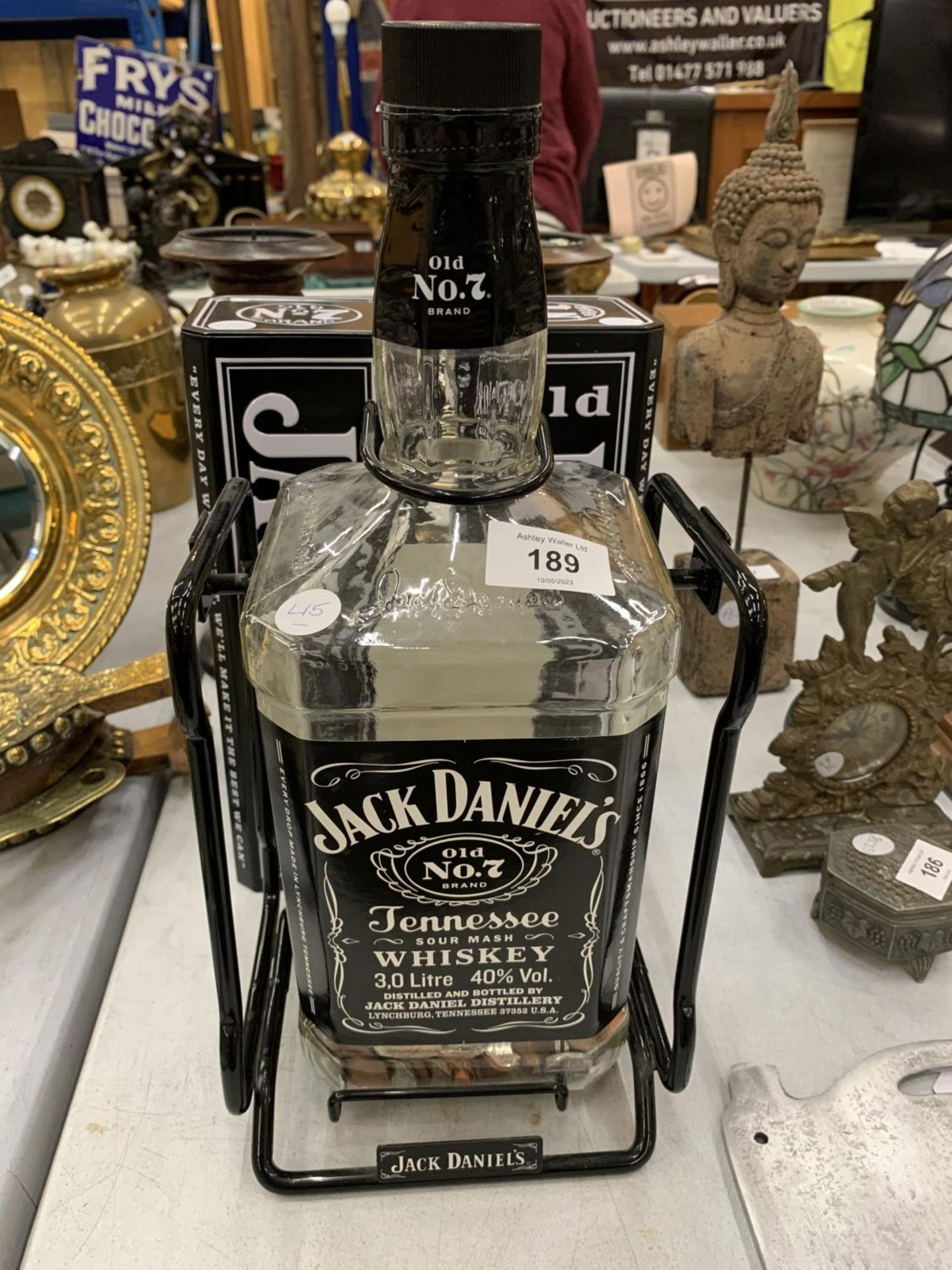 A JACK DANIELS SWINGING BOTTLE STAND WITH LARGE JACK DANIELS BOTTLE CONTAINING COINS PLUS TWO