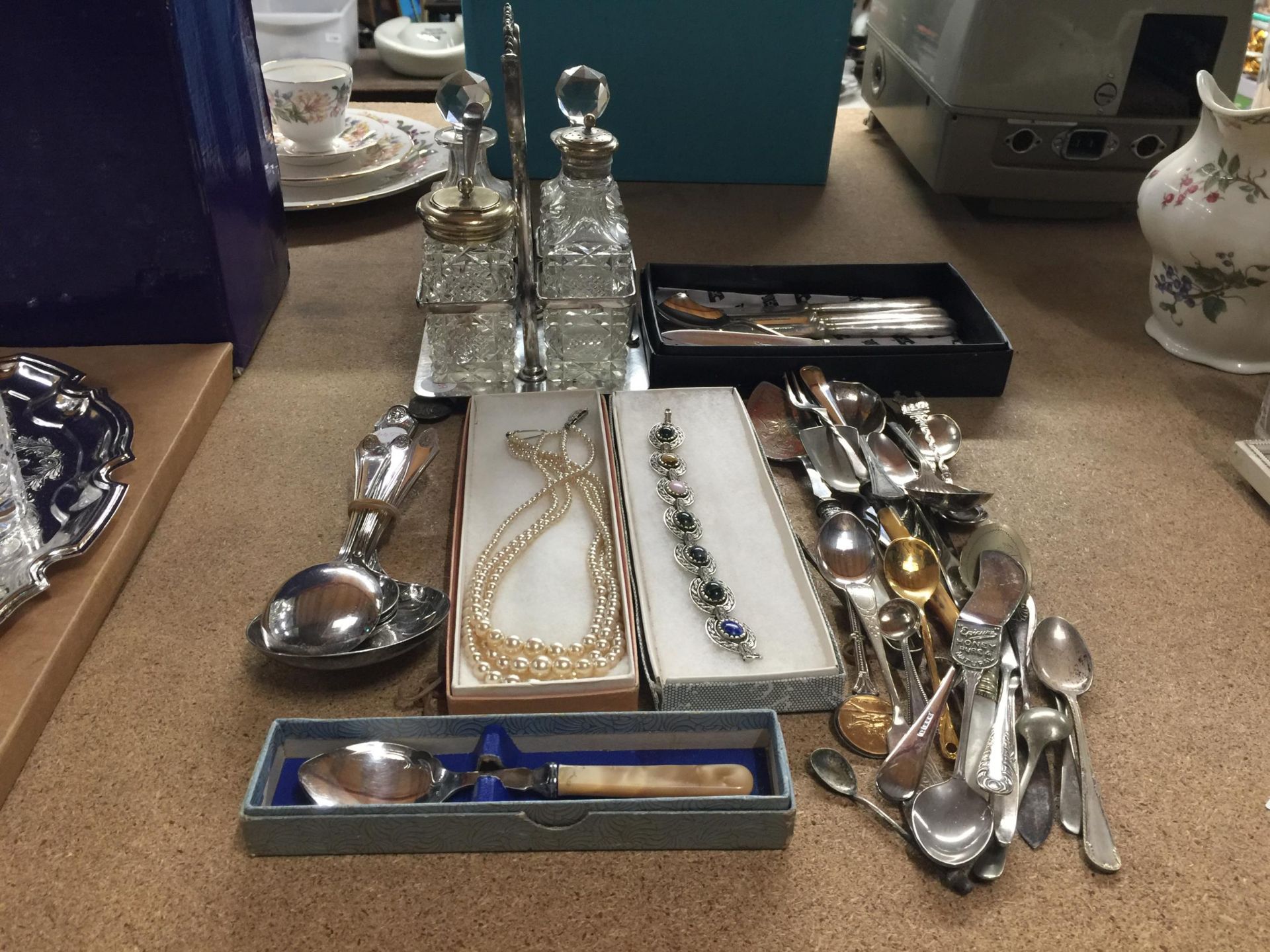 A MIXED LOT TO INCLUDE A SILVER PLATED CRUET STAND WITH GLASS BOTTLES, SOUVENIR TEASPOONS, FLATWARE,