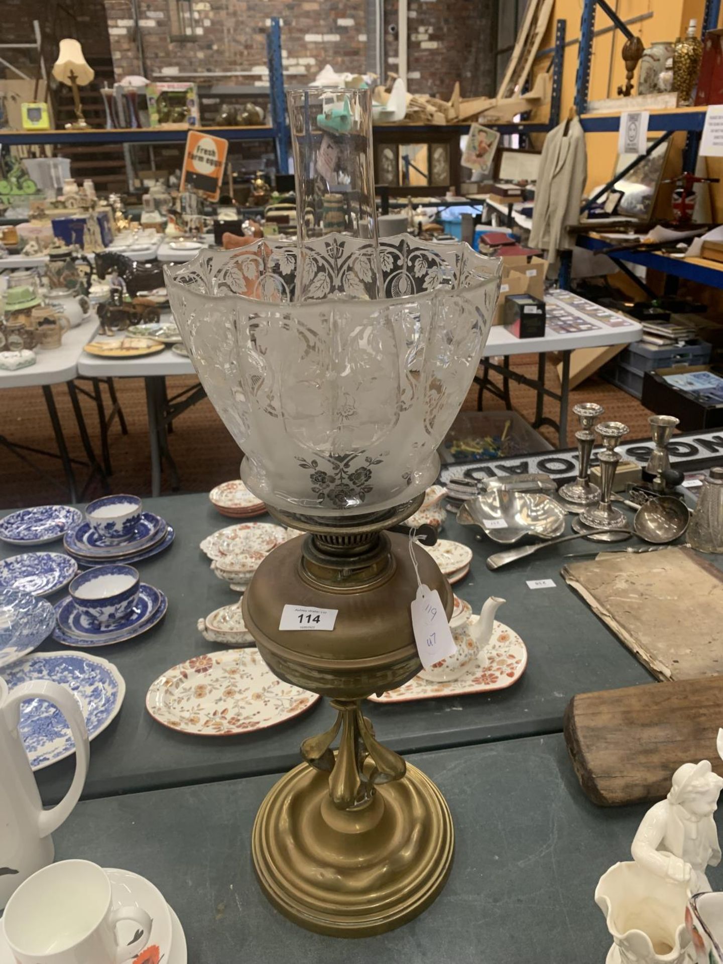 A VINTAGE ARTS AND CRAFTS STYLE BRASS OIL LAMP WITH CHIMNEY AND DECORATED GLASS SHADE HEIGHT 50CM TO