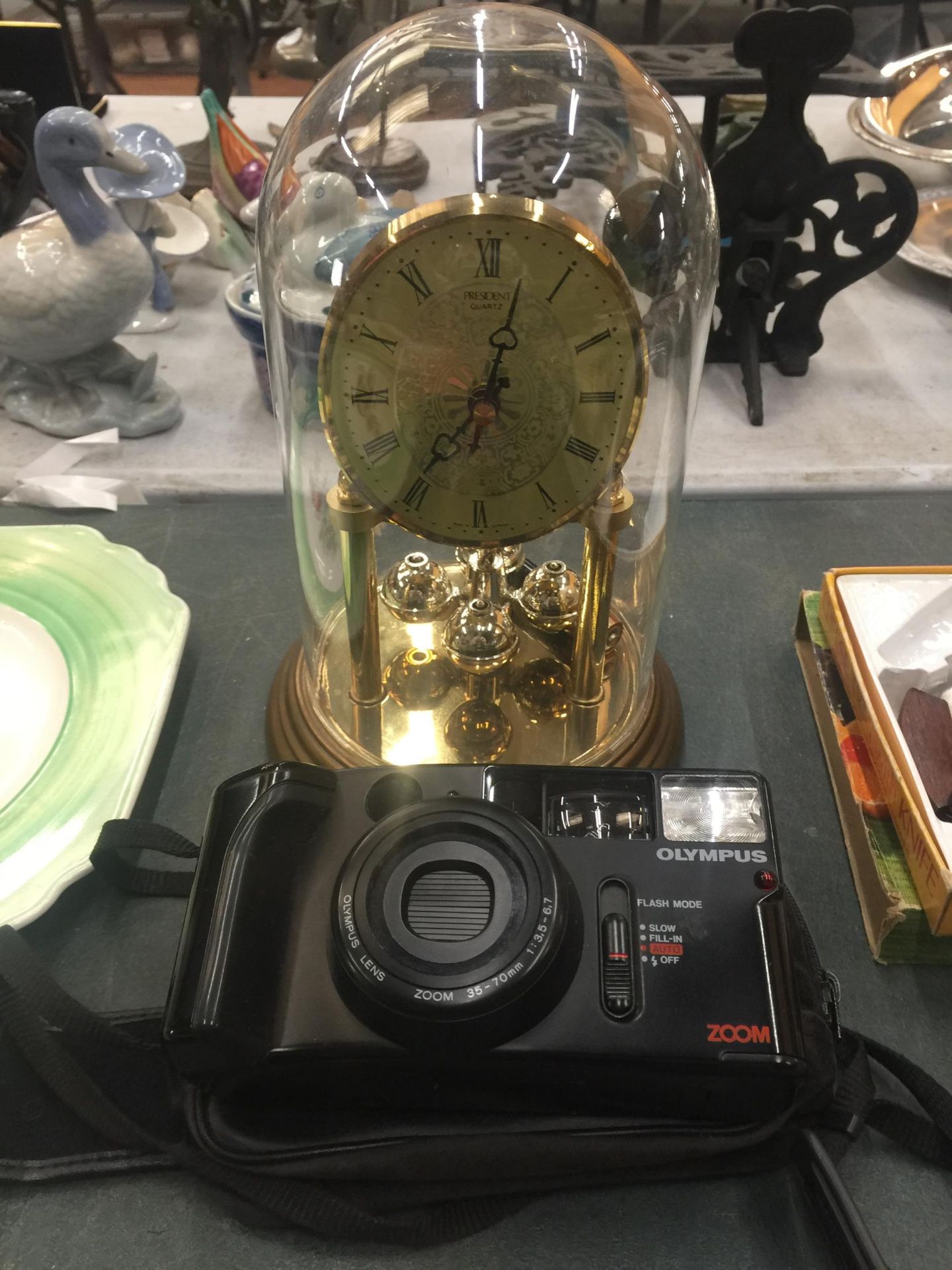 AN OLYMPUS AZ-1 ZOOM IN A CARRY CASE PLUS AN ANNIVERSARY MANTLE CLOCK WITH A GLASS DOME