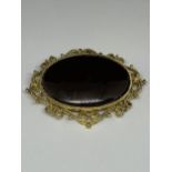 A LARGE BROOCH WITH BLACK STONE WITH ORNATE YELLOW METAL SURROUND MARKED 250 WITH PRESENTATION BAG