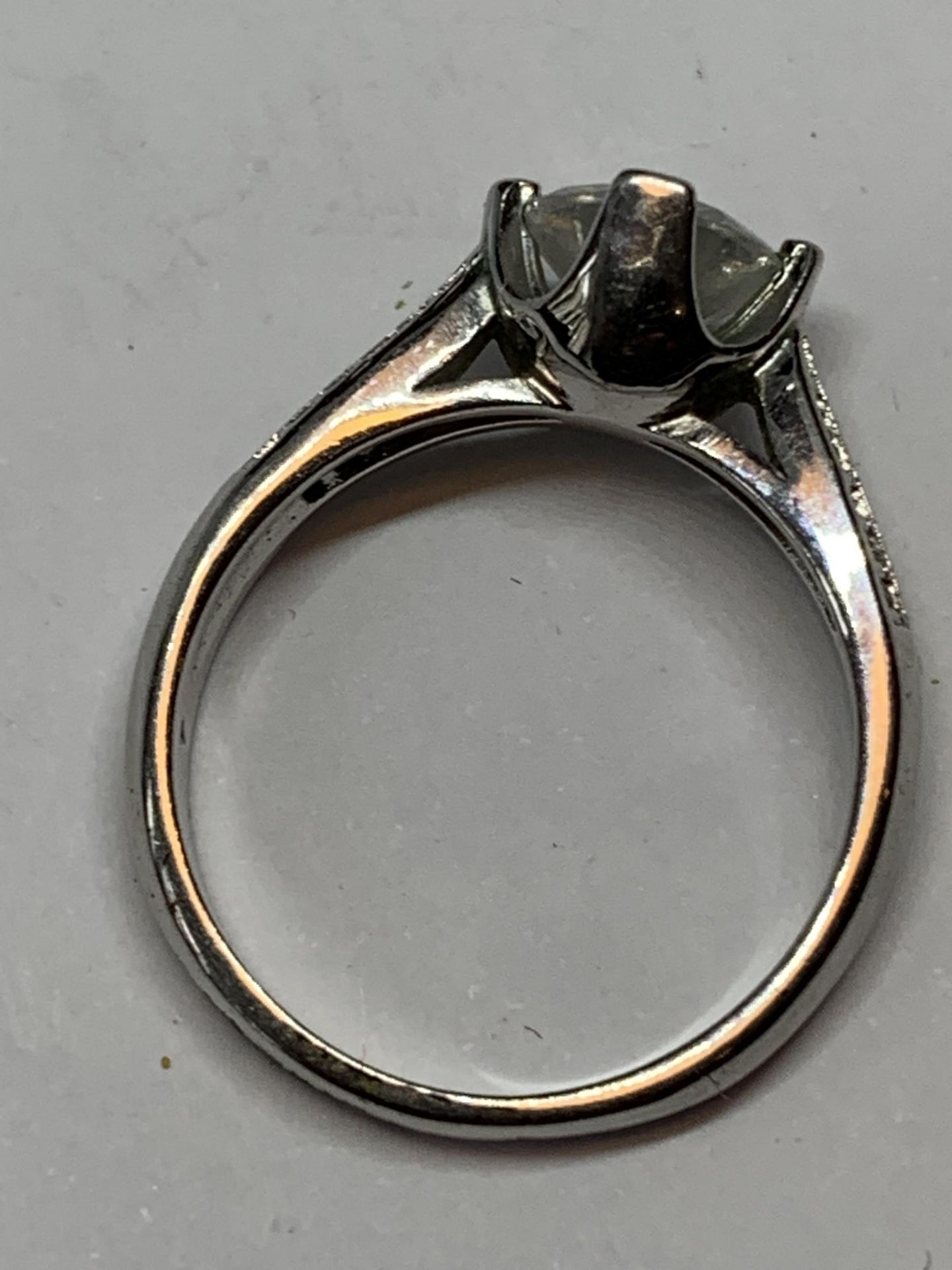 A SILVER RING WITH A LARGE SOLITAIRE CLEAR STONE AND CLEARSTONES TOO SHOULDERS SIZE M/N IN A - Image 3 of 4