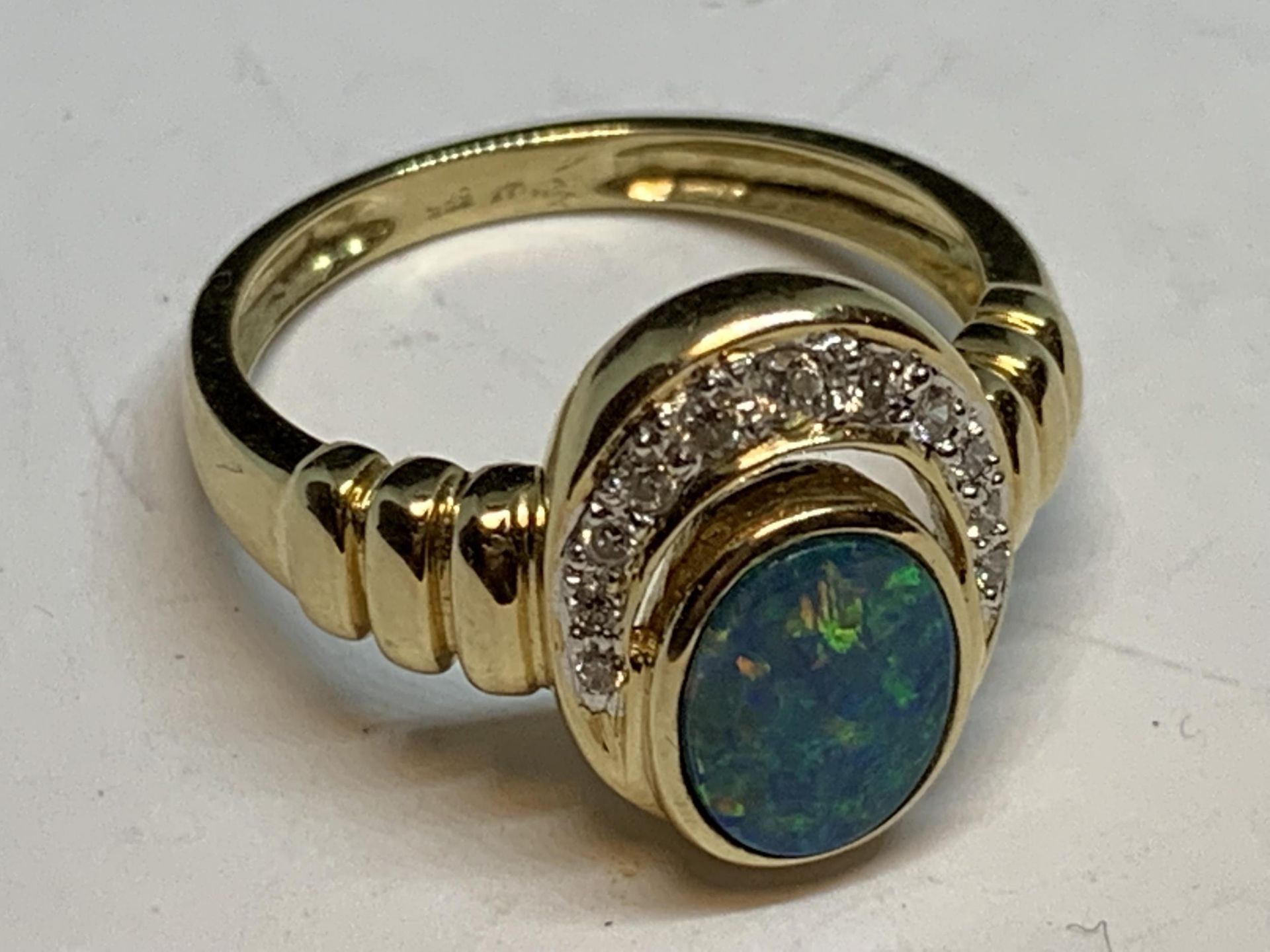A 14 CARAT GOLD RING WITH A CENTRE OPAL SURROUNDED BY DIAMONDS GROSS WEIGHT 3.84 GRAMS SIZE M/N WITH