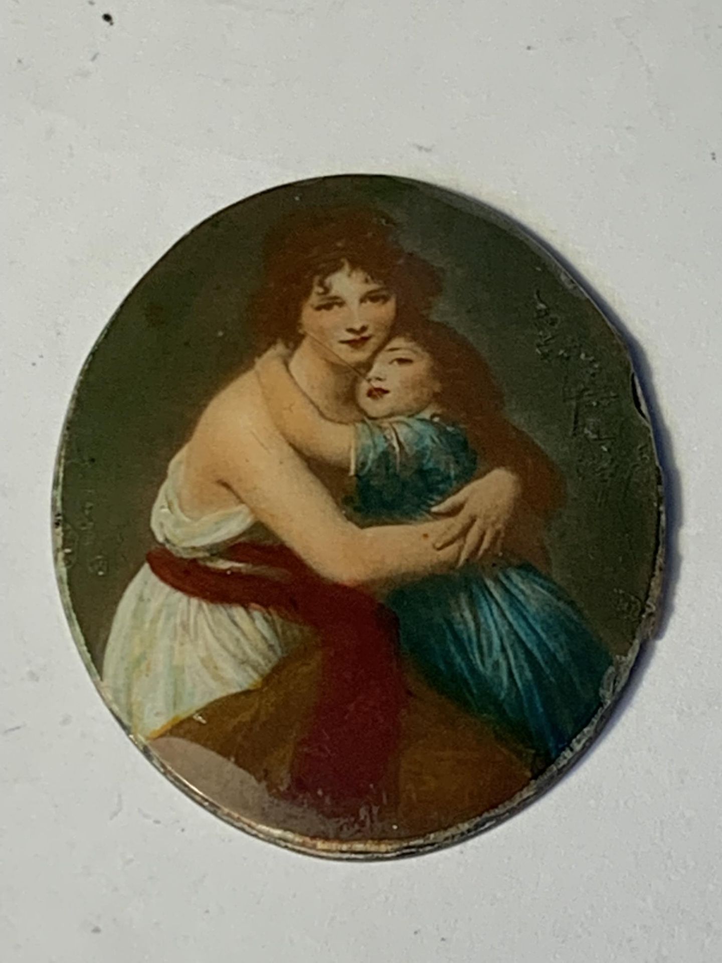 AN ENAMEL DISC OF A MOTHER AND CHILD