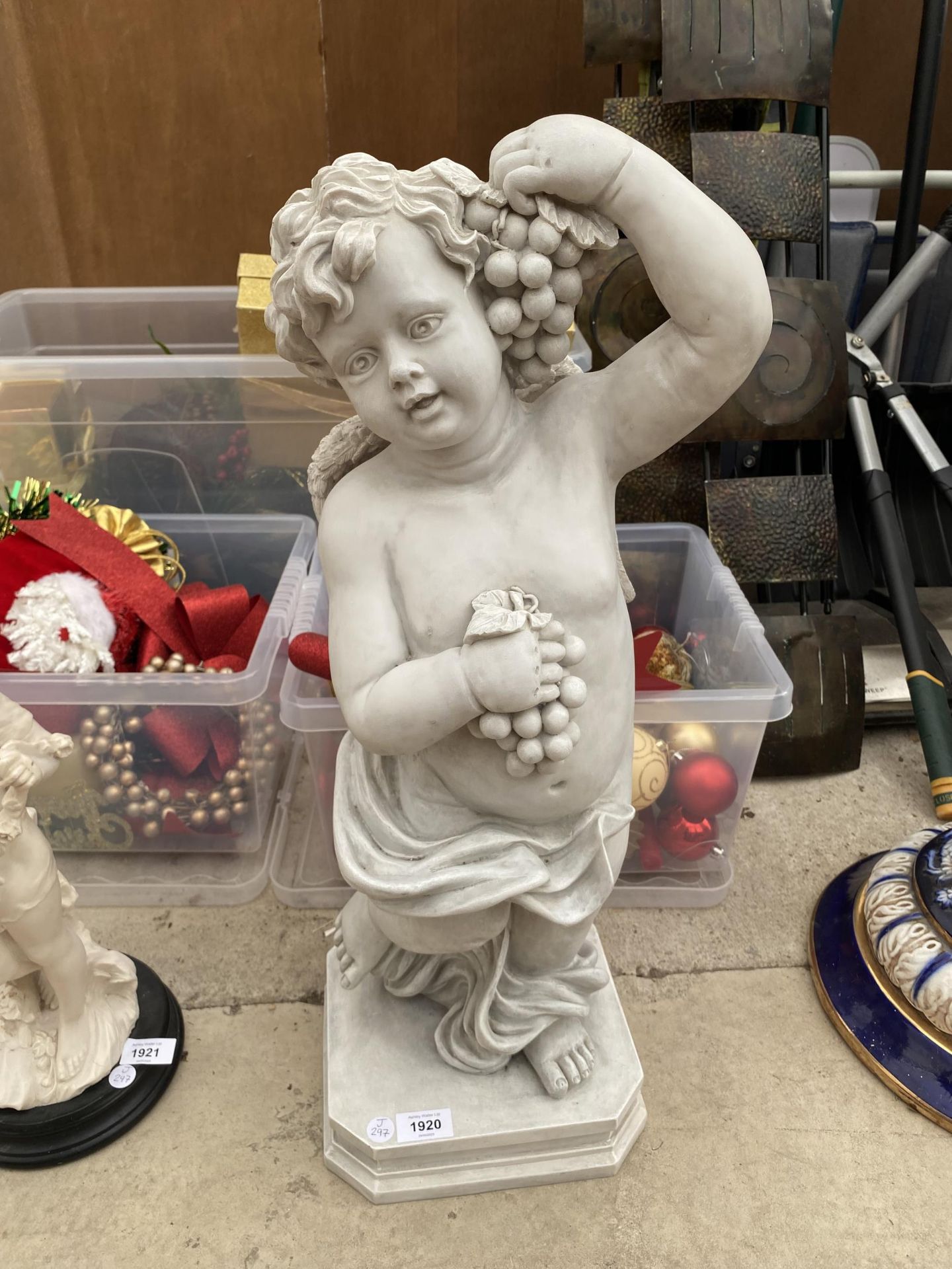 A RESIN TYPE MODEL OF A CHERUB HOLDING GRAPES
