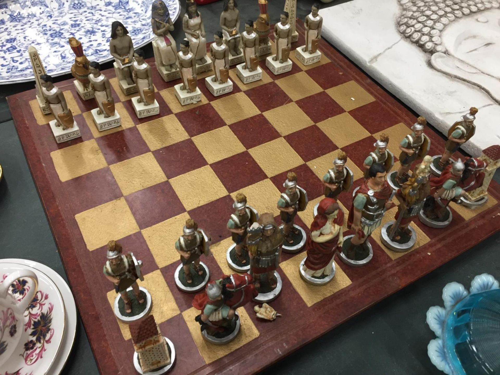 A HEAVY VINTAGE CHESS BOARD COMPLETE WITH ROMANS AND EGYPTIANS CHESS PIECES