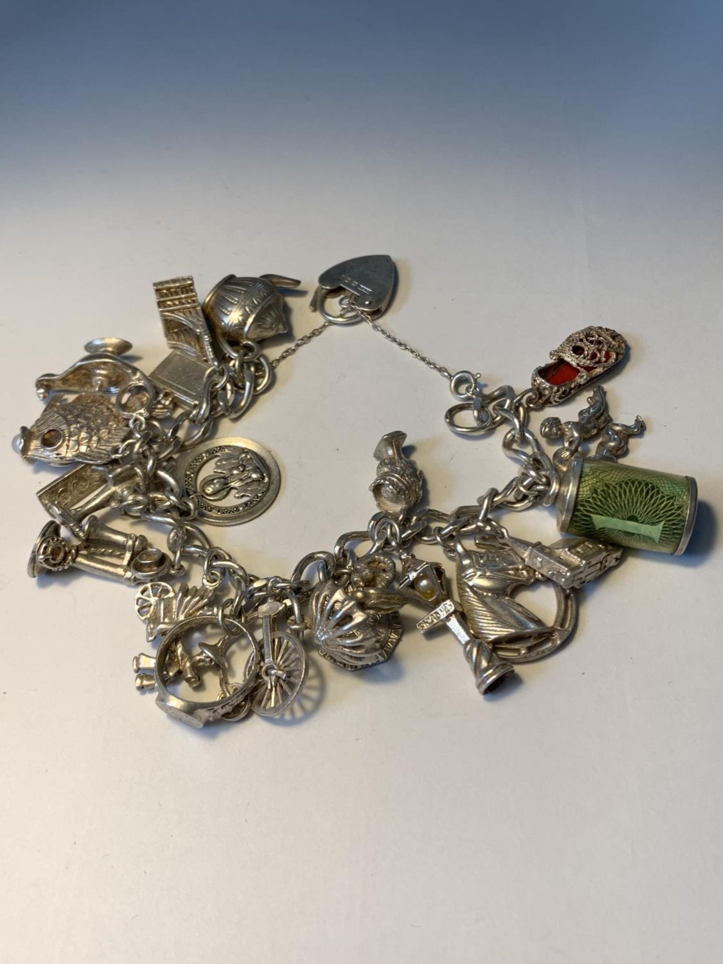 A SILVER CHARM BRACELET WITH TWENTY CHARMS AND A HALLMARKED LONDON SILVER HEART CLASP