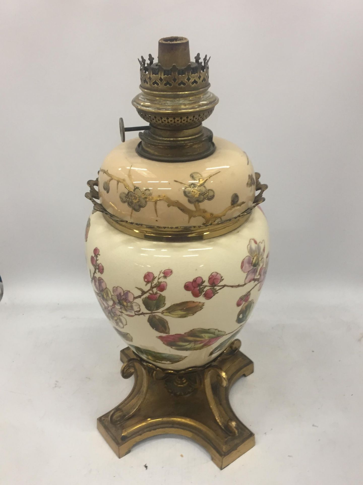 AN ANTIQUE CERAMIC AND BRASS OIL LAMP WITH FLORAL DESIGN