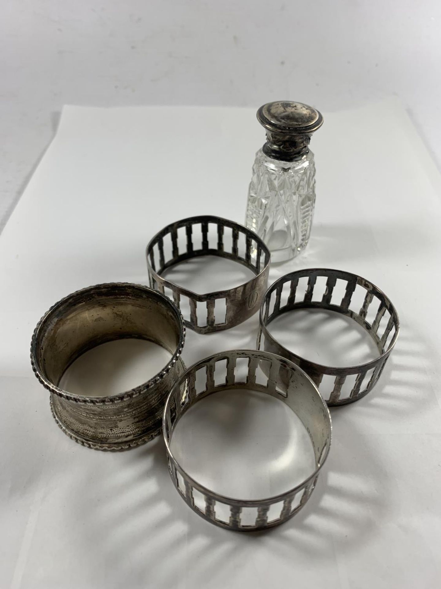 FOUR SILVER NAPKIN RINGS AND A SILVER LIDDED PERFUME BOTTLE WITH STOPPER