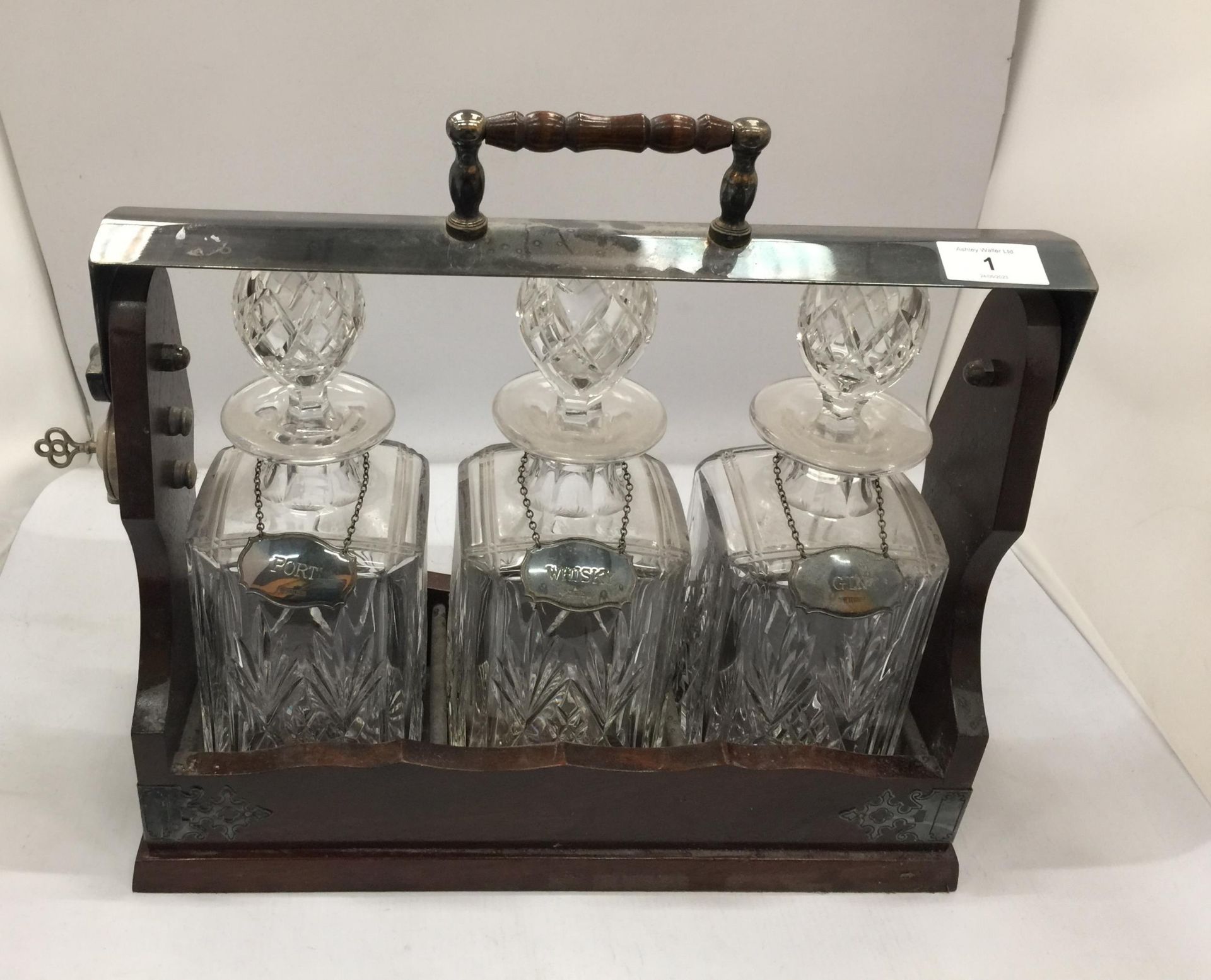 A VINTAGE THREE BOTTLE TANTULUS WITH THREE CUT GLASS DECANTERS, ALL WITH HALLMARKED SILVER
