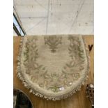 A SMALL OVAL CREAM PATTERNED FRINGED RUG