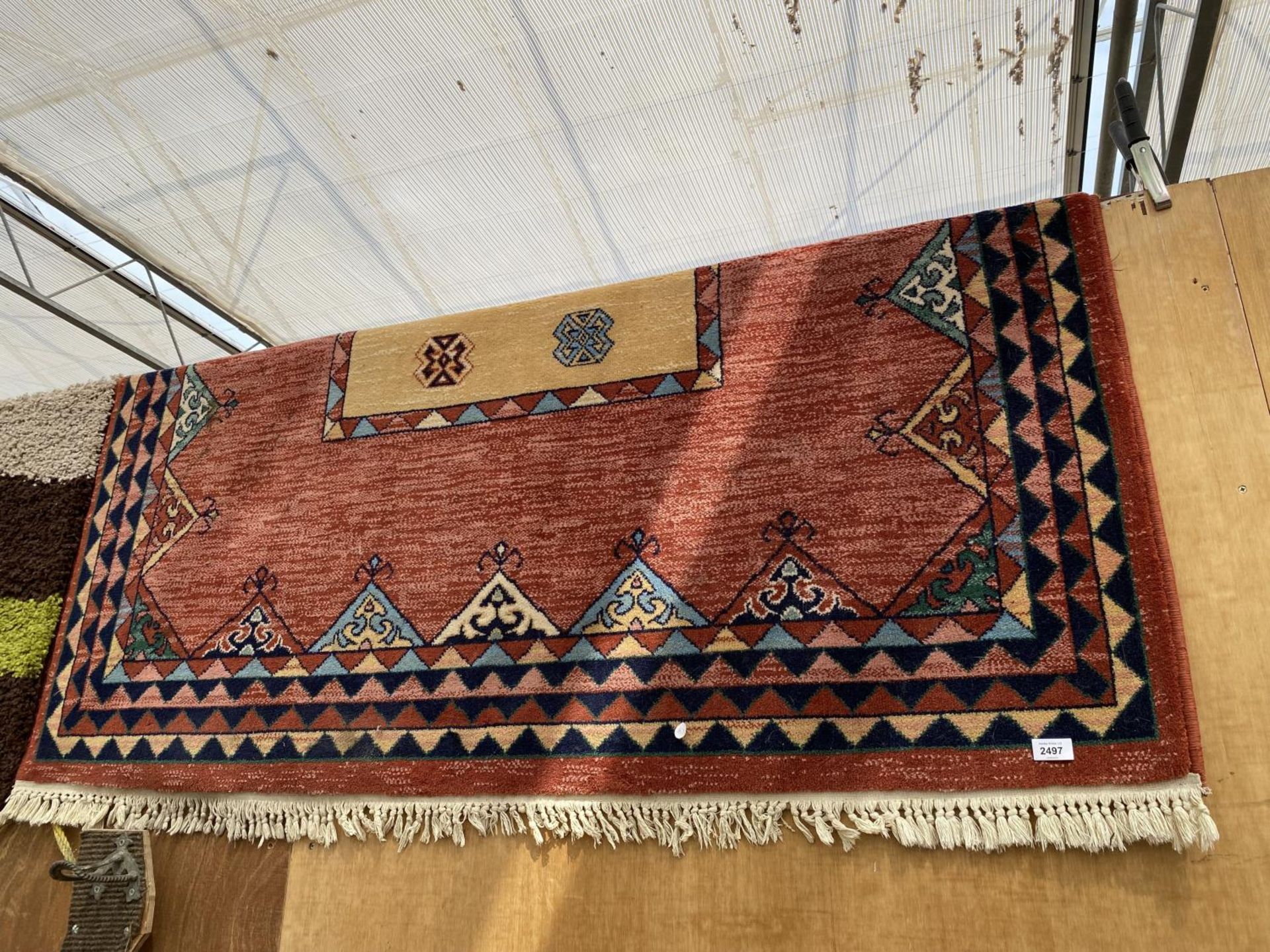 A RED PATTERNED FRINGED RUG