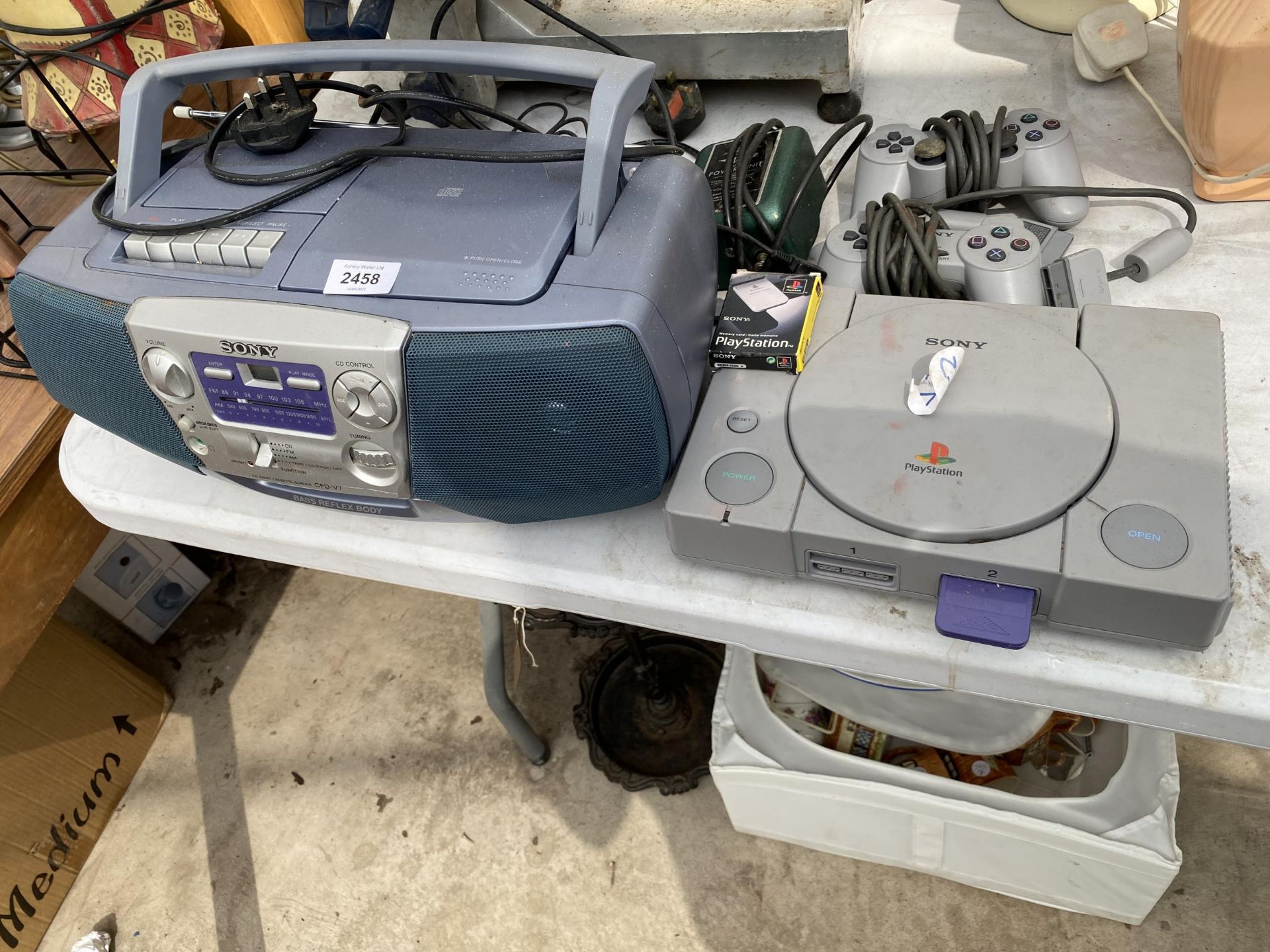 A SONY PLAYSTATION ONE WITH TWO CONTROLLERS AND A SONY RADIO