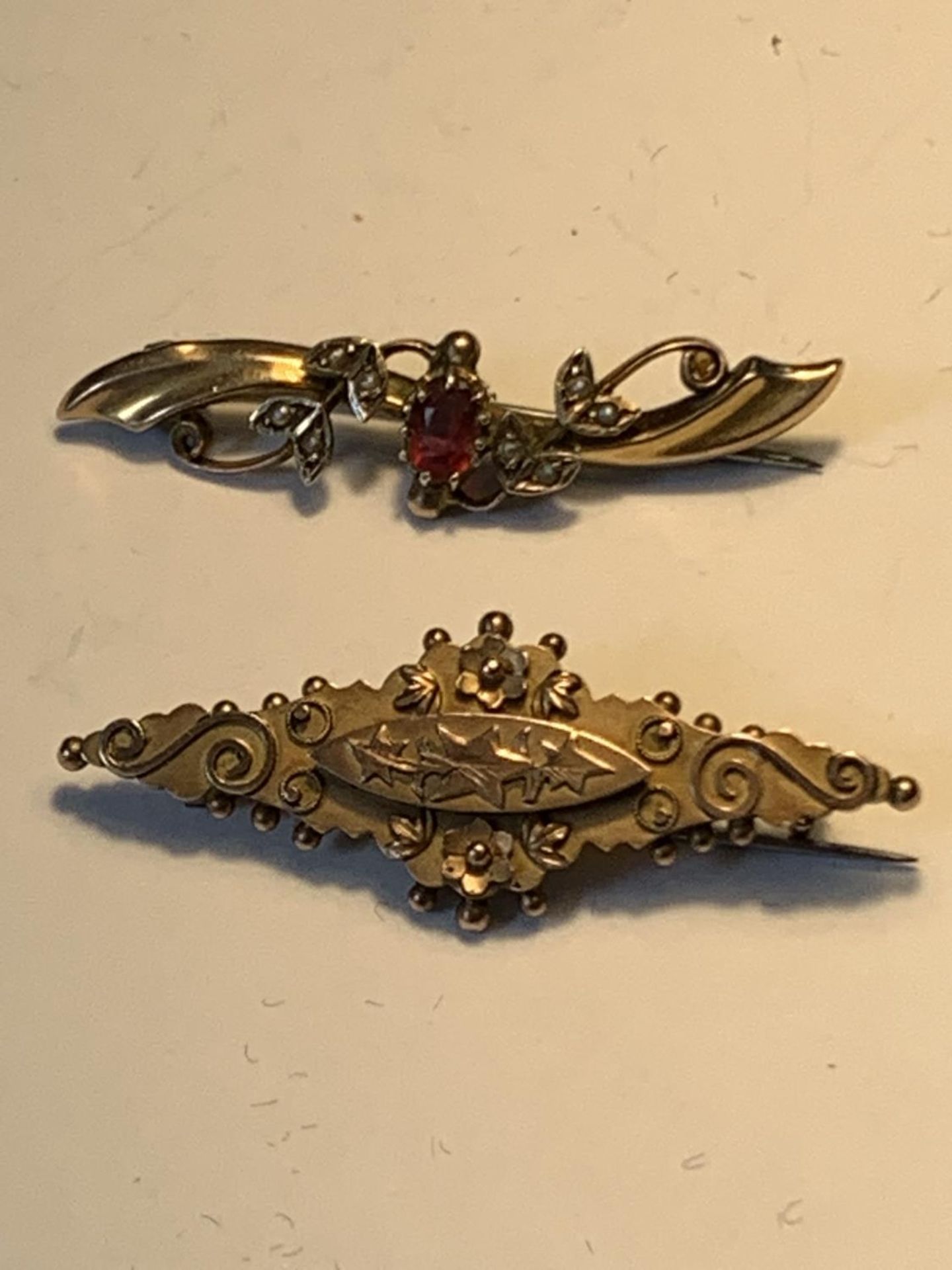 TWO 9 CARAT GOLD BROOCHES ONE WITH A RED STONE AND SEED PEARLS GROSS WEIGHT 5.05 GRAMS