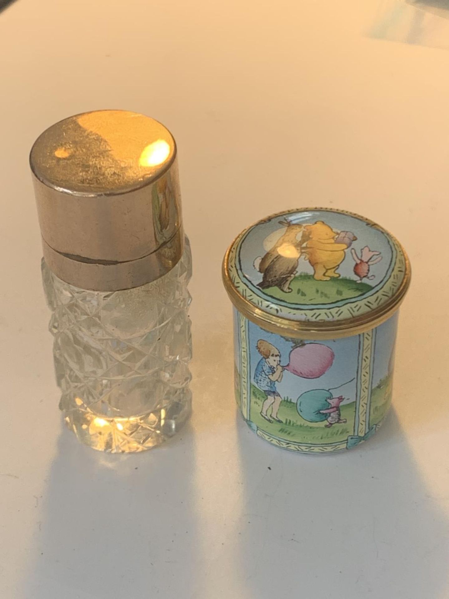 A HAND PAINTED ENAMEL POT DEPICTING POOH BEAR AND A GOLD PLATED PERFUME BOTTLE