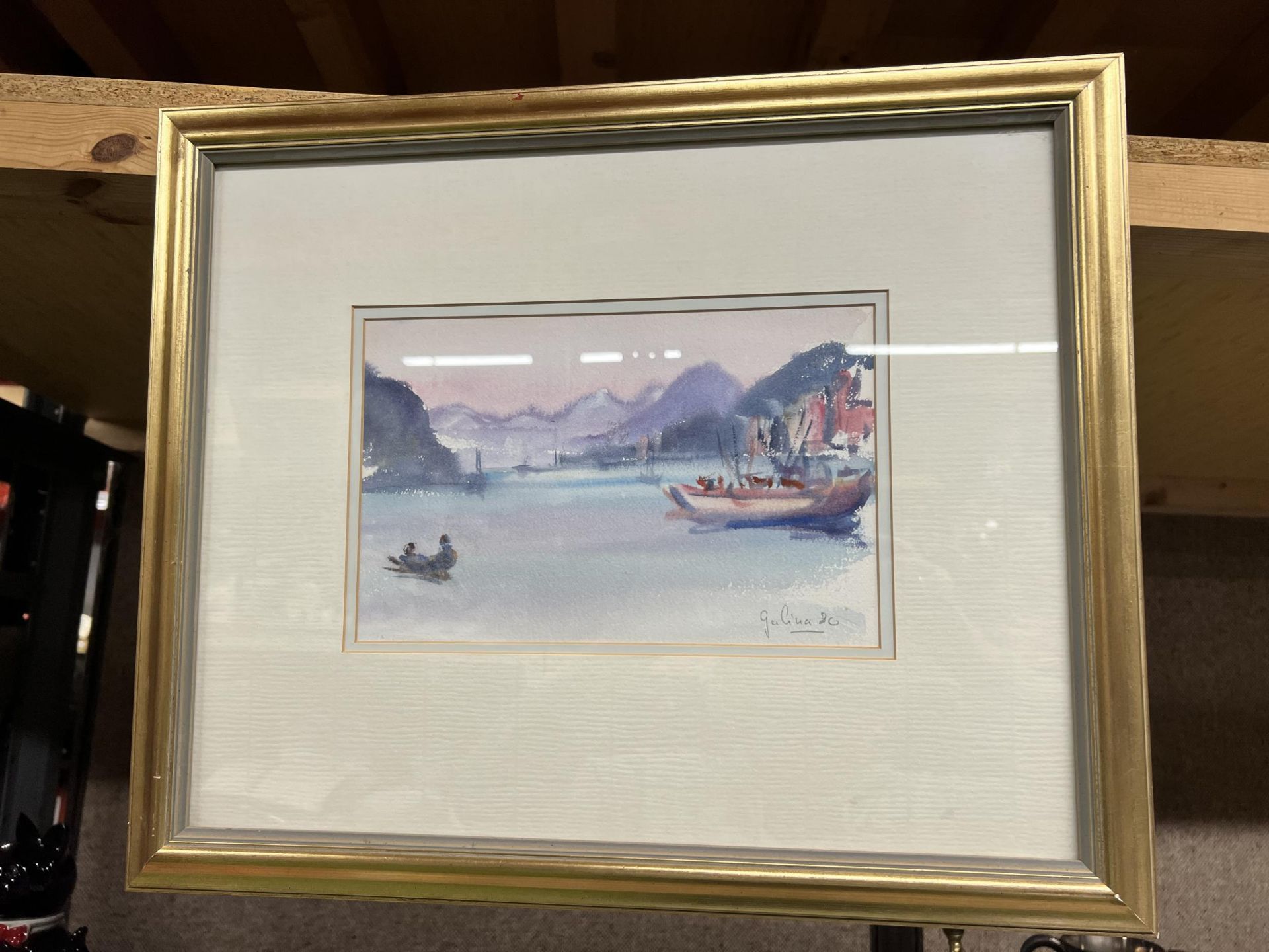 A FRAMED WATERCOLOUR OF A BOAT SCENE WITH MOUNTAINS SIGNED