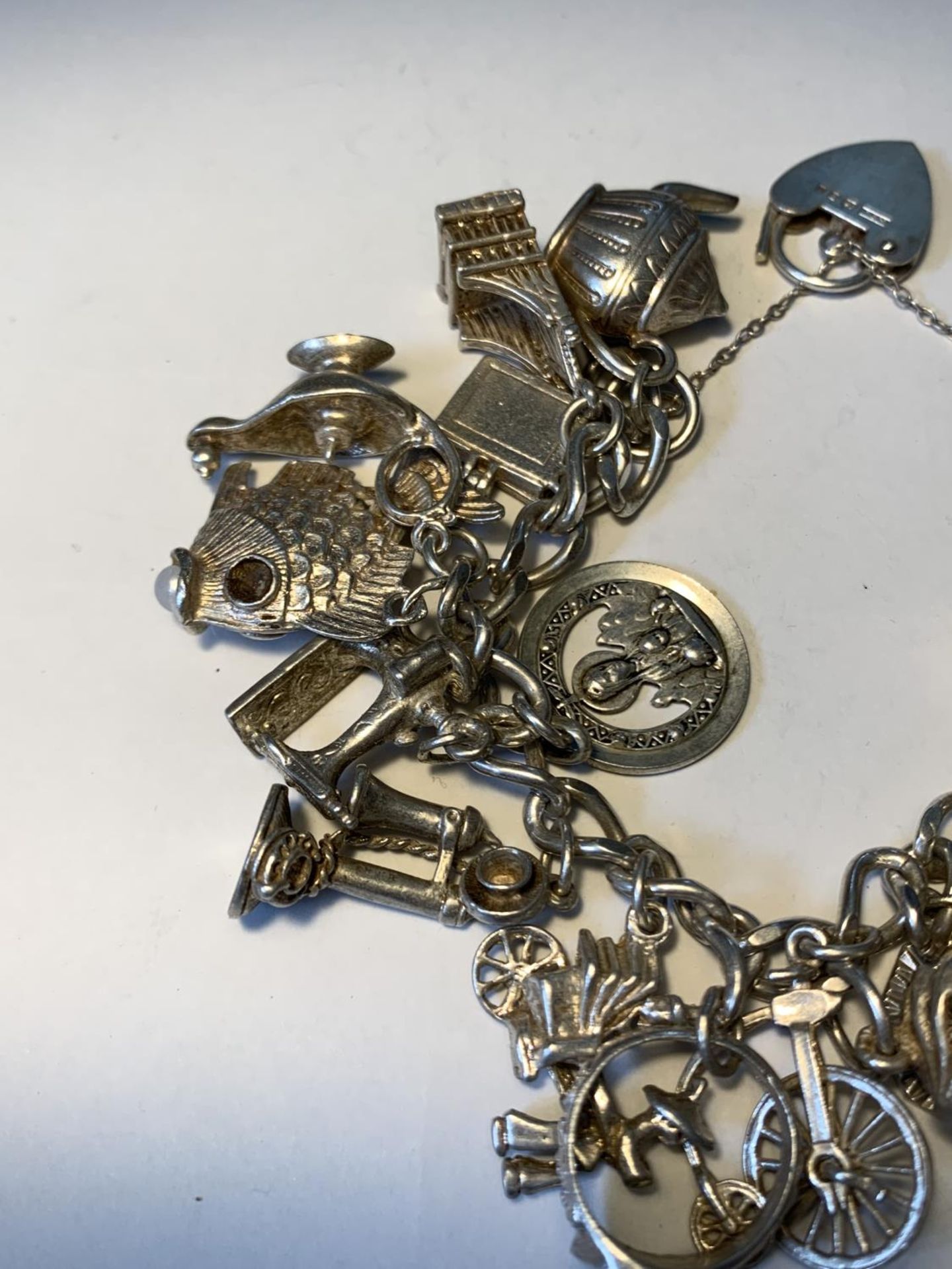 A SILVER CHARM BRACELET WITH TWENTY CHARMS AND A HALLMARKED LONDON SILVER HEART CLASP - Image 4 of 5