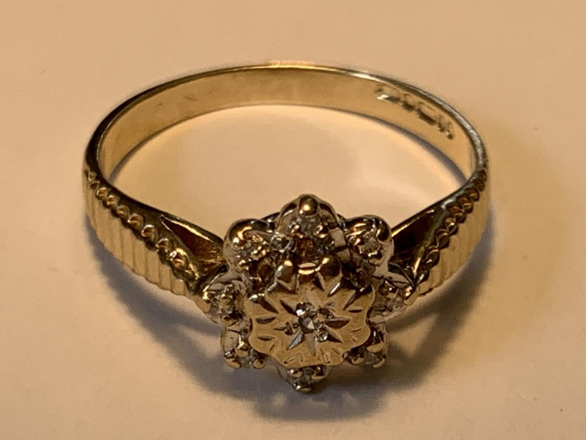 A 9 CARAT GOLD DIAMOND RING IN THE STYLE OF A DAISY SIZE K