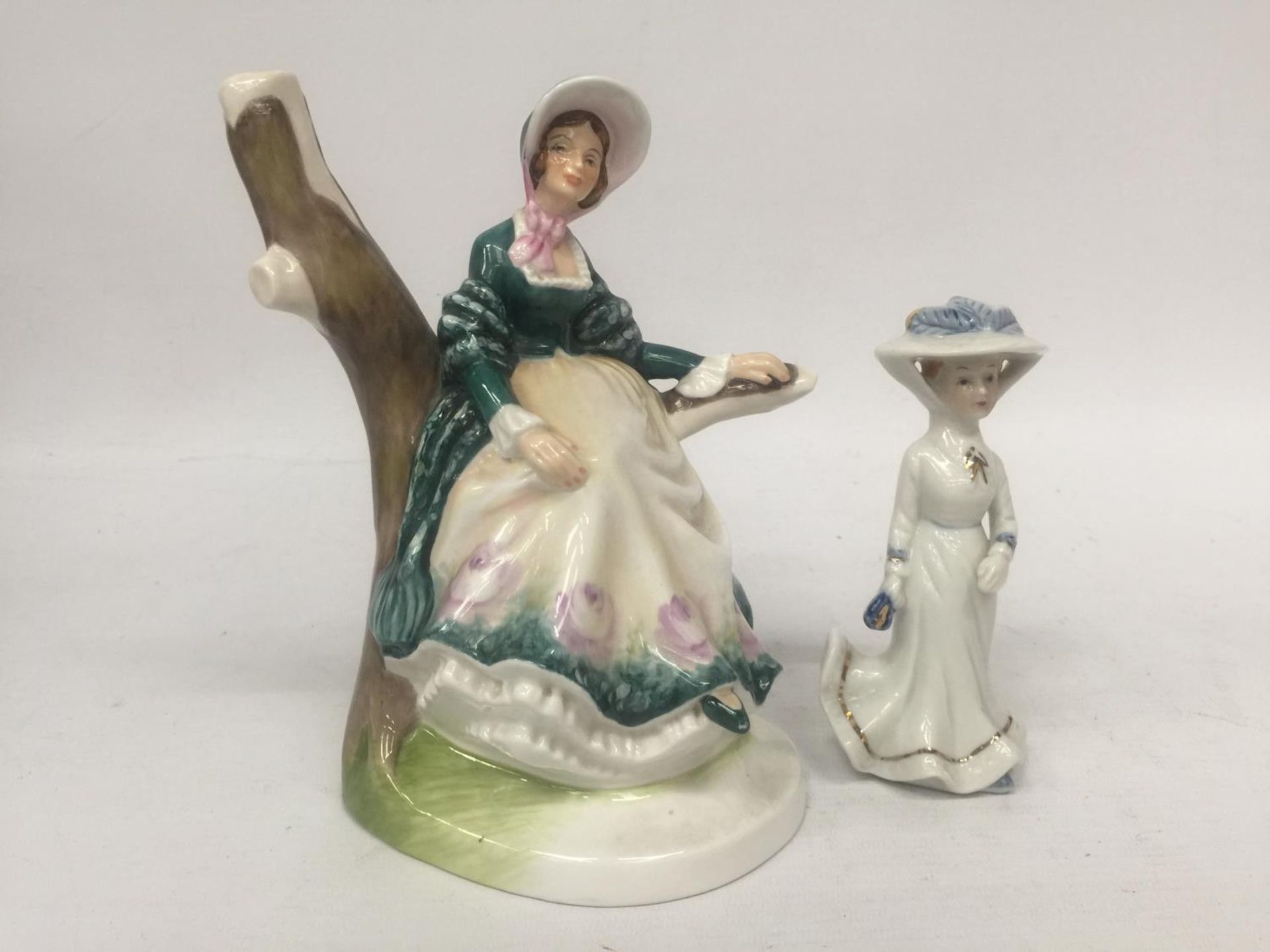 A FINE BONE CHINA FIGURE OF A LADY SITTING IN A BRANCH "EMILY" TOGETHER WITH A SMALL PORCELAIN LADY