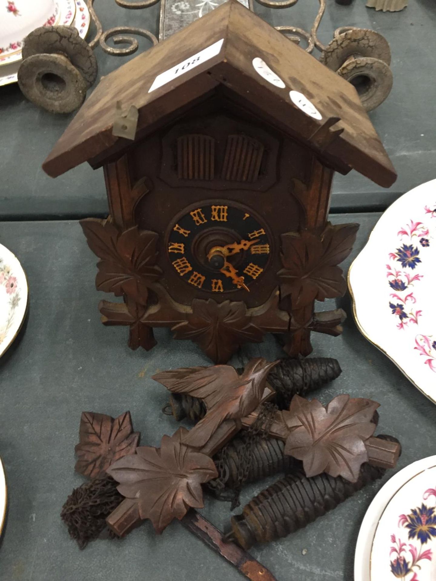 A WOODEN CUCKOO CLOCK COMPLETE WITH PENDULUM AND WEIGHTS