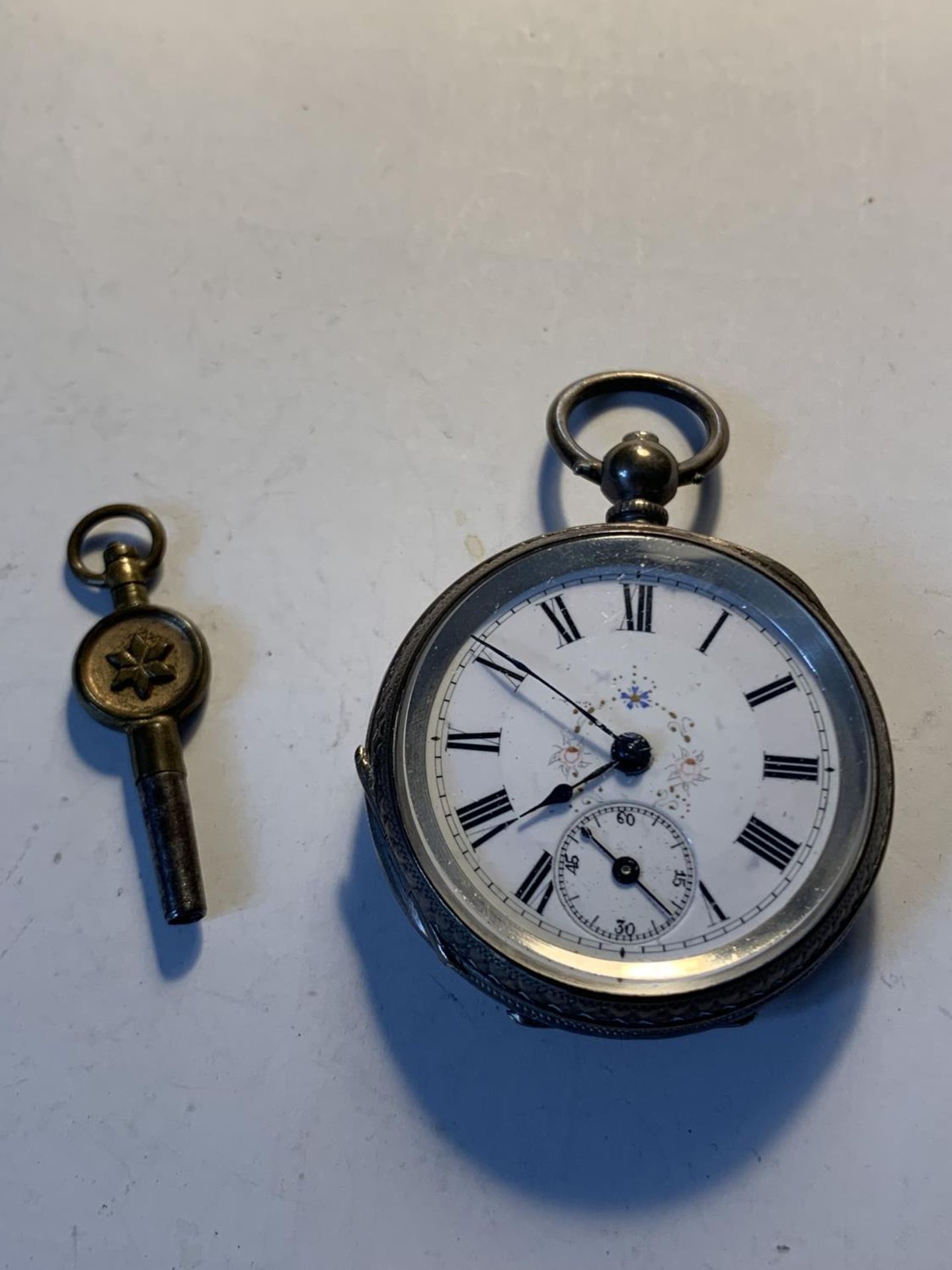 AN 800 SILVER POCKET WATCH WITH SUB DIAL, DECORATIVE WHITE ENAMEL FACE, ROMAN NUMERALS AND A KEY