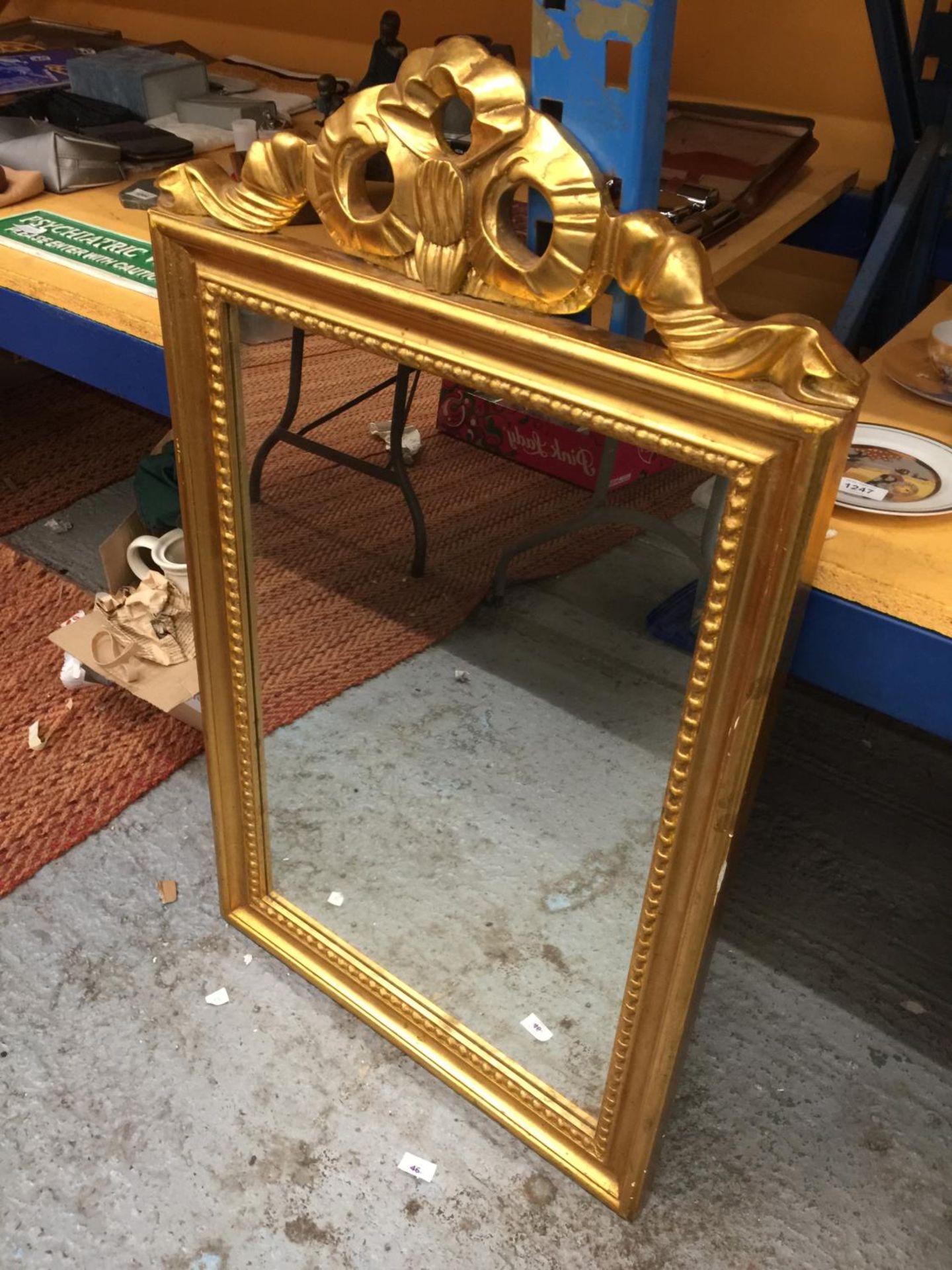 AN ORNATE GILT FRAMED MIRROR WITH RIBBON DESIGN TOP