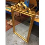 AN ORNATE GILT FRAMED MIRROR WITH RIBBON DESIGN TOP